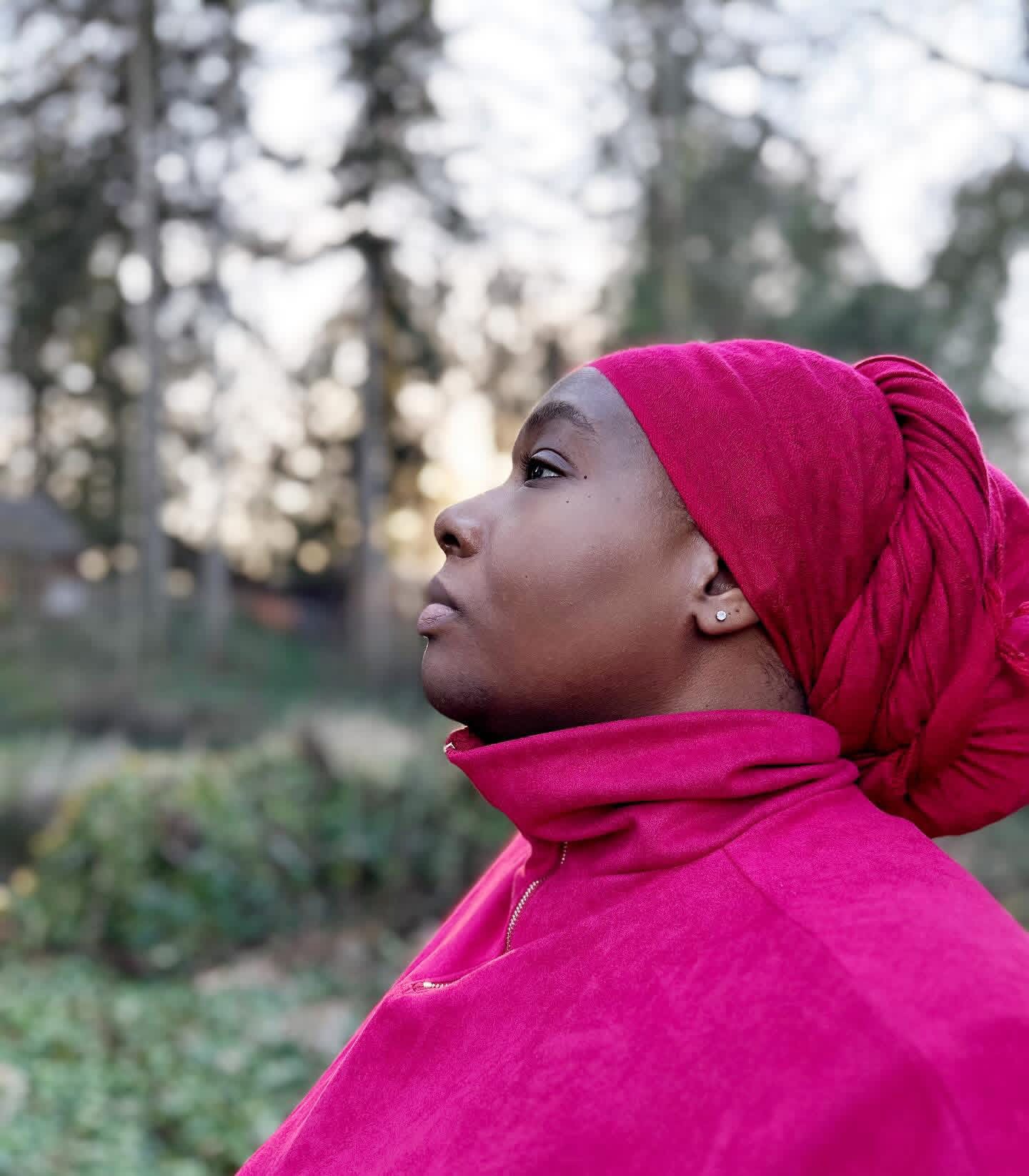 a woman in a red turban looking out into the woods