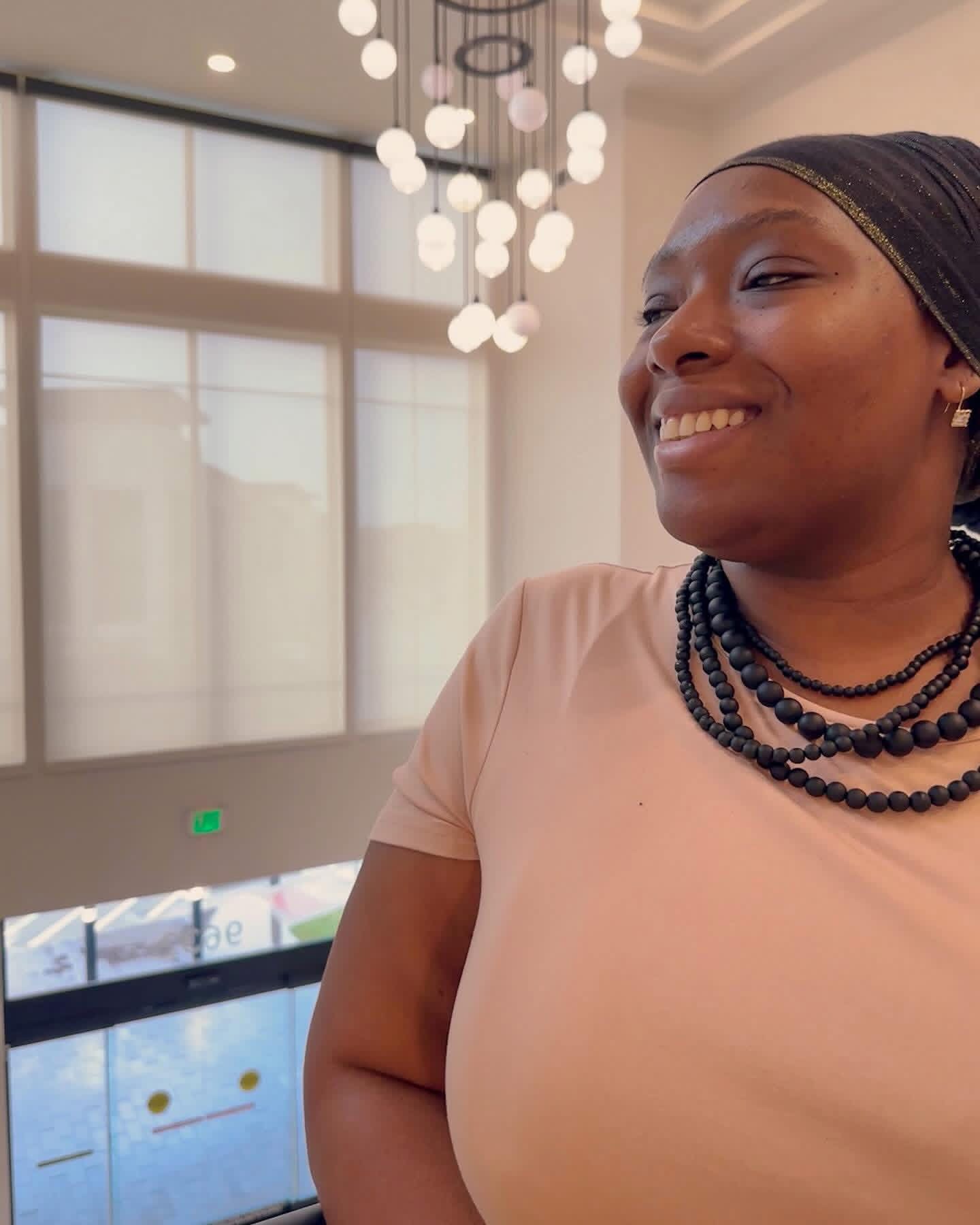 a woman wearing a turban smiles in front of a chandelier