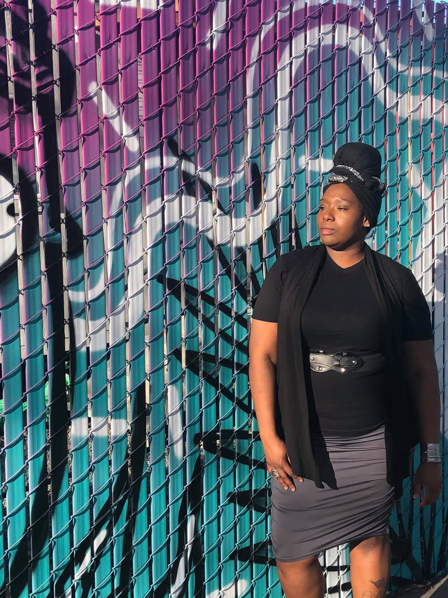 a black woman standing in front of a graffiti wall