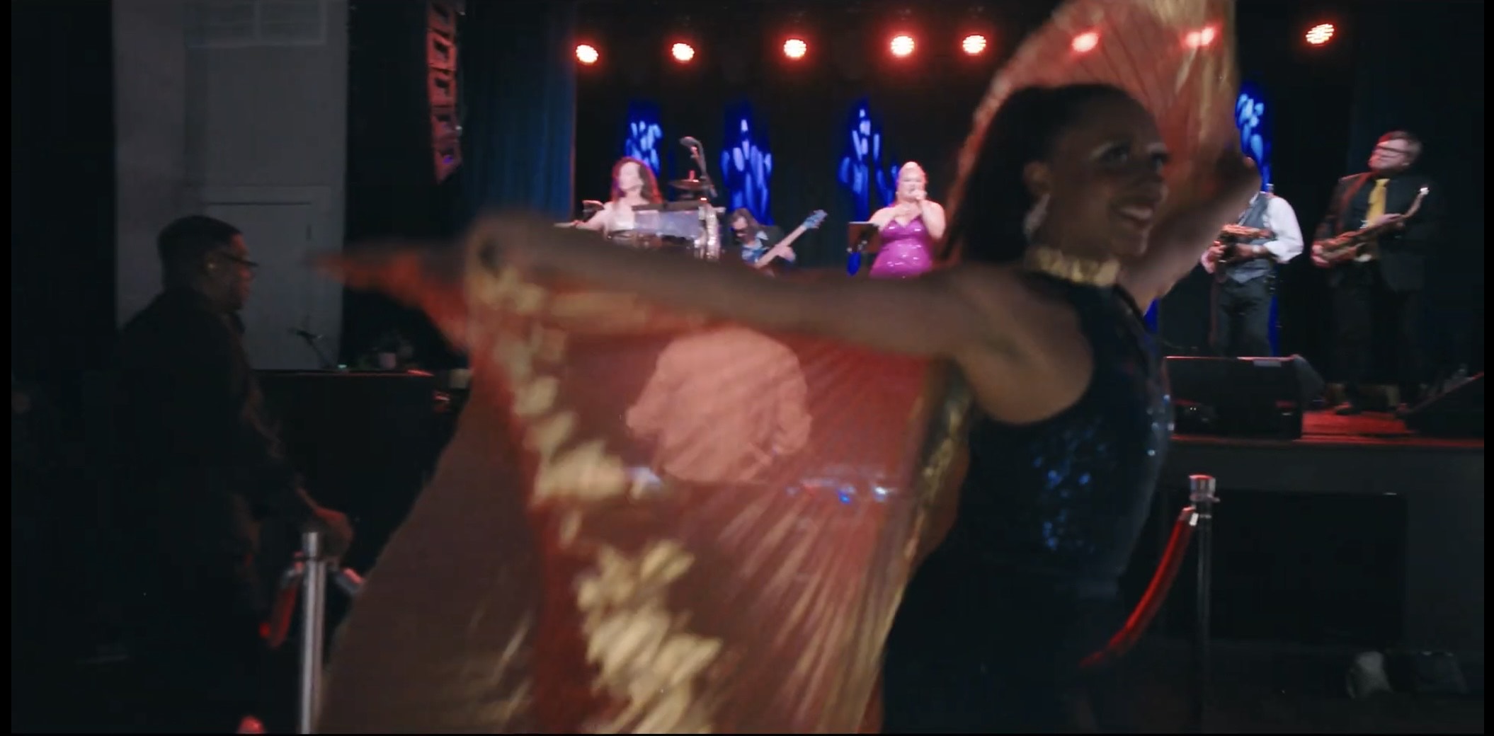 a woman is dancing on stage with a band