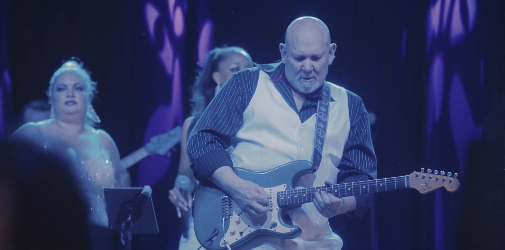 a man playing an electric guitar in front of a group of people