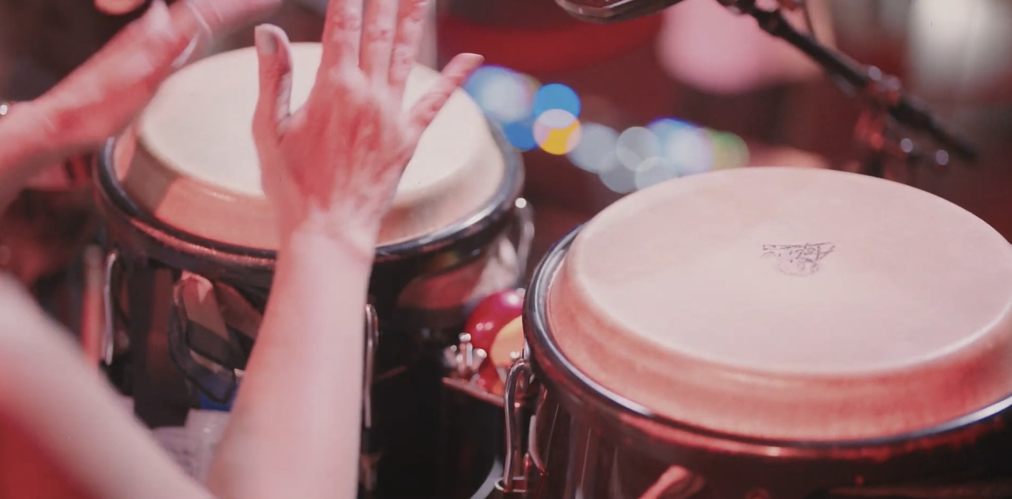 a woman is playing a conga drum with her hands