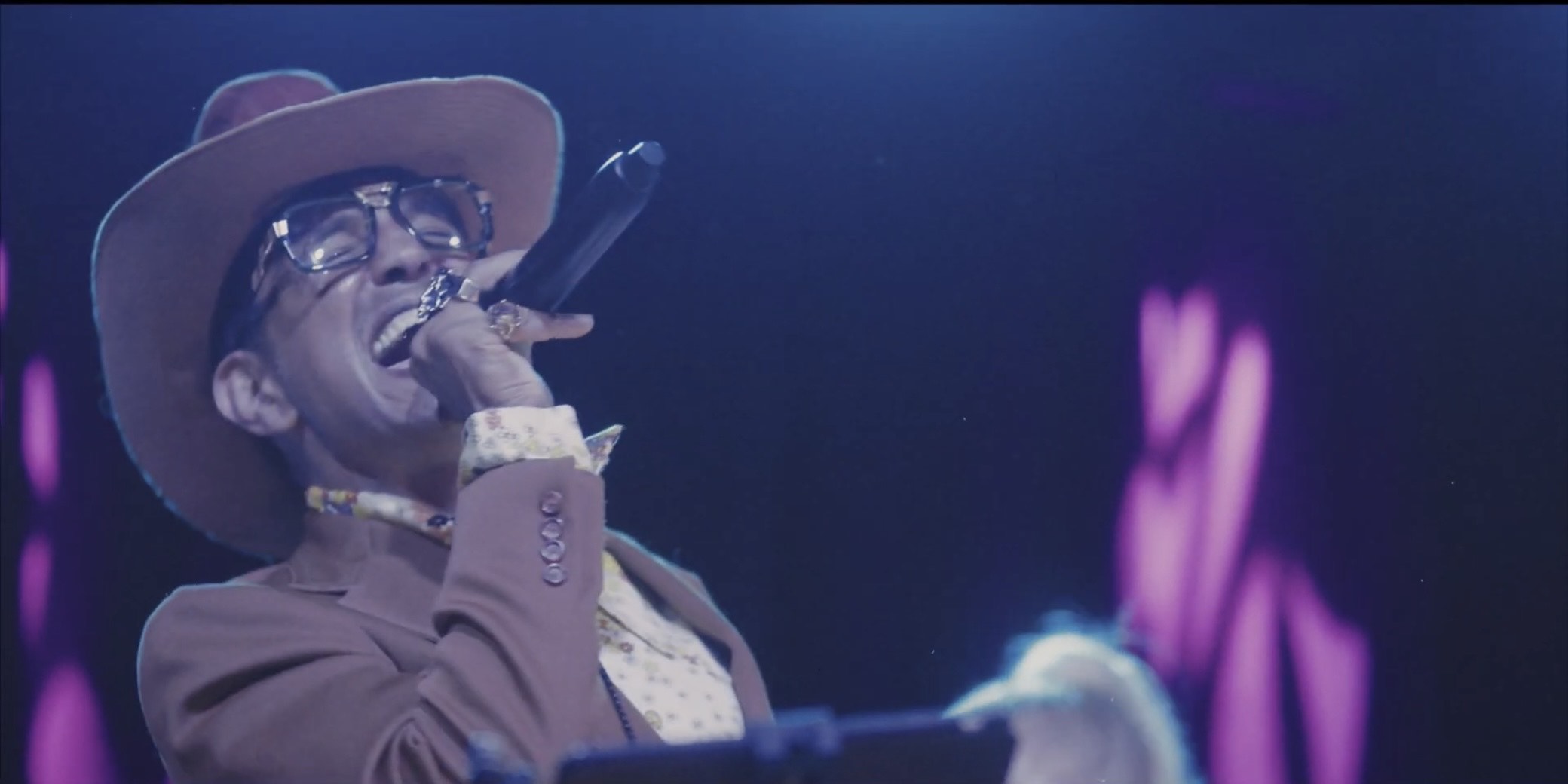 a man in a brown hat singing into a microphone