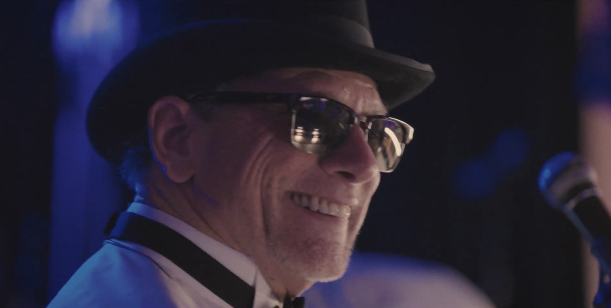 a man in a top hat and sunglasses singing into a microphone