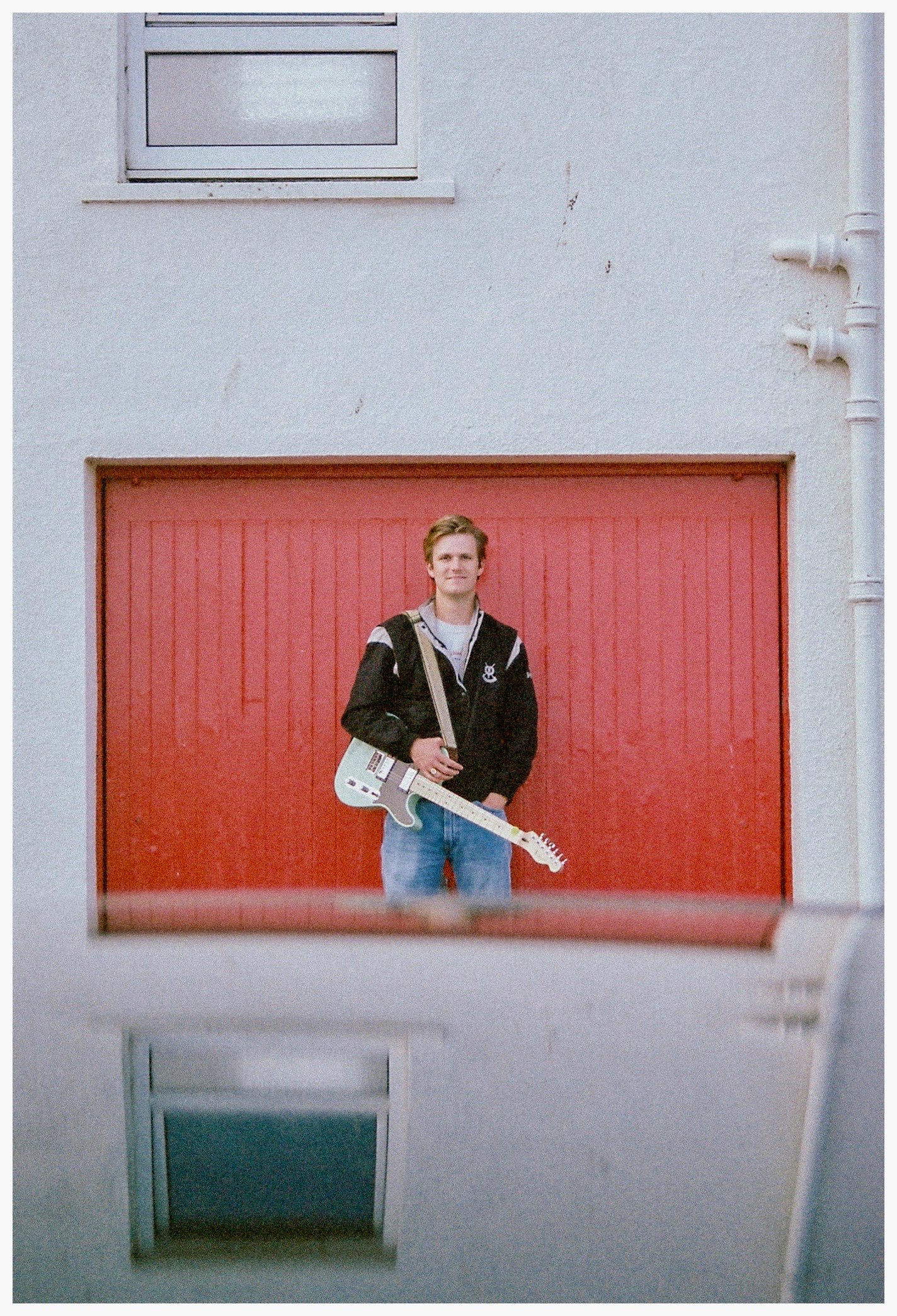 a man holding a guitar in front of a red building
