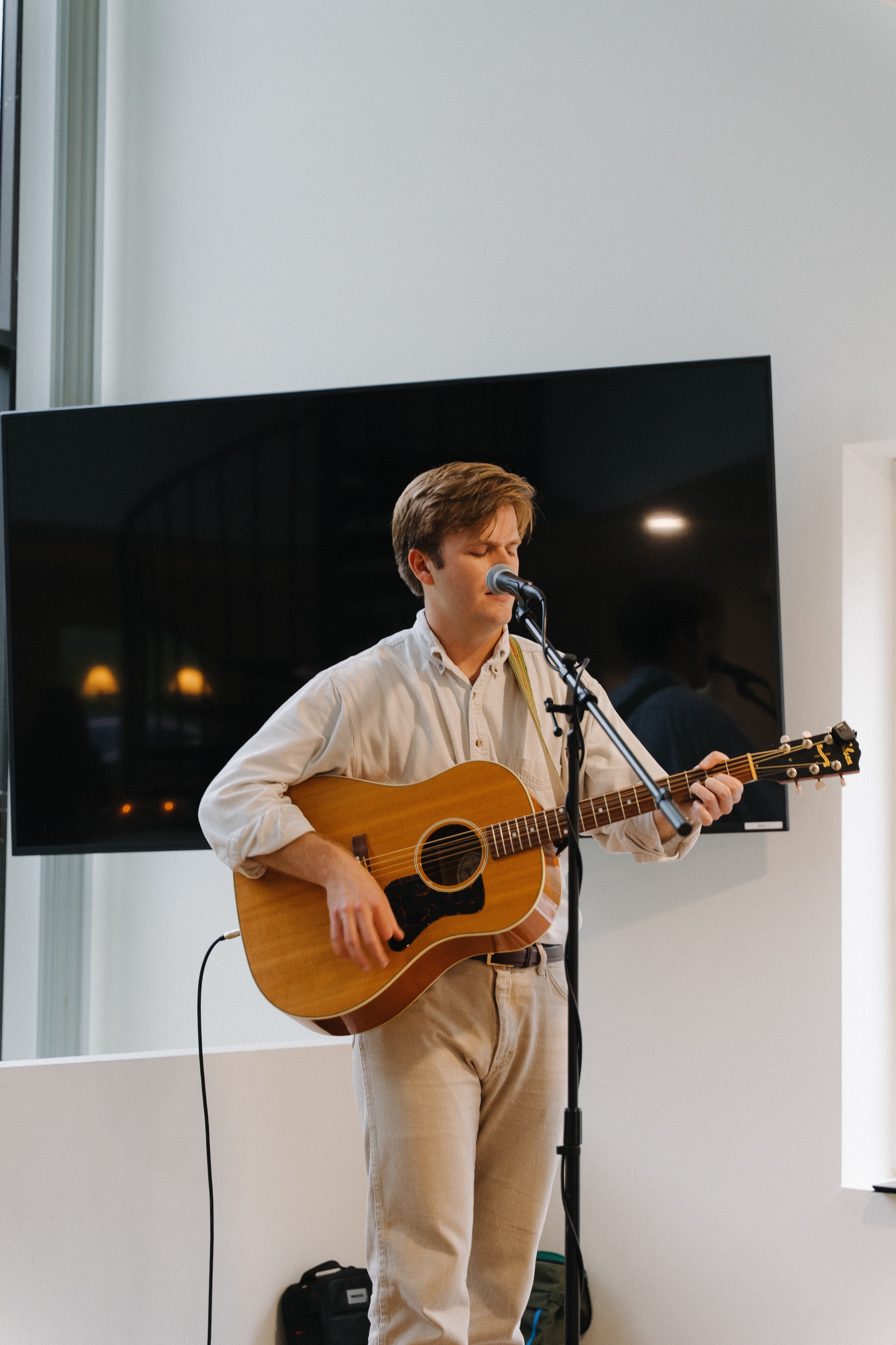a man playing an acoustic guitar in front of a microphone