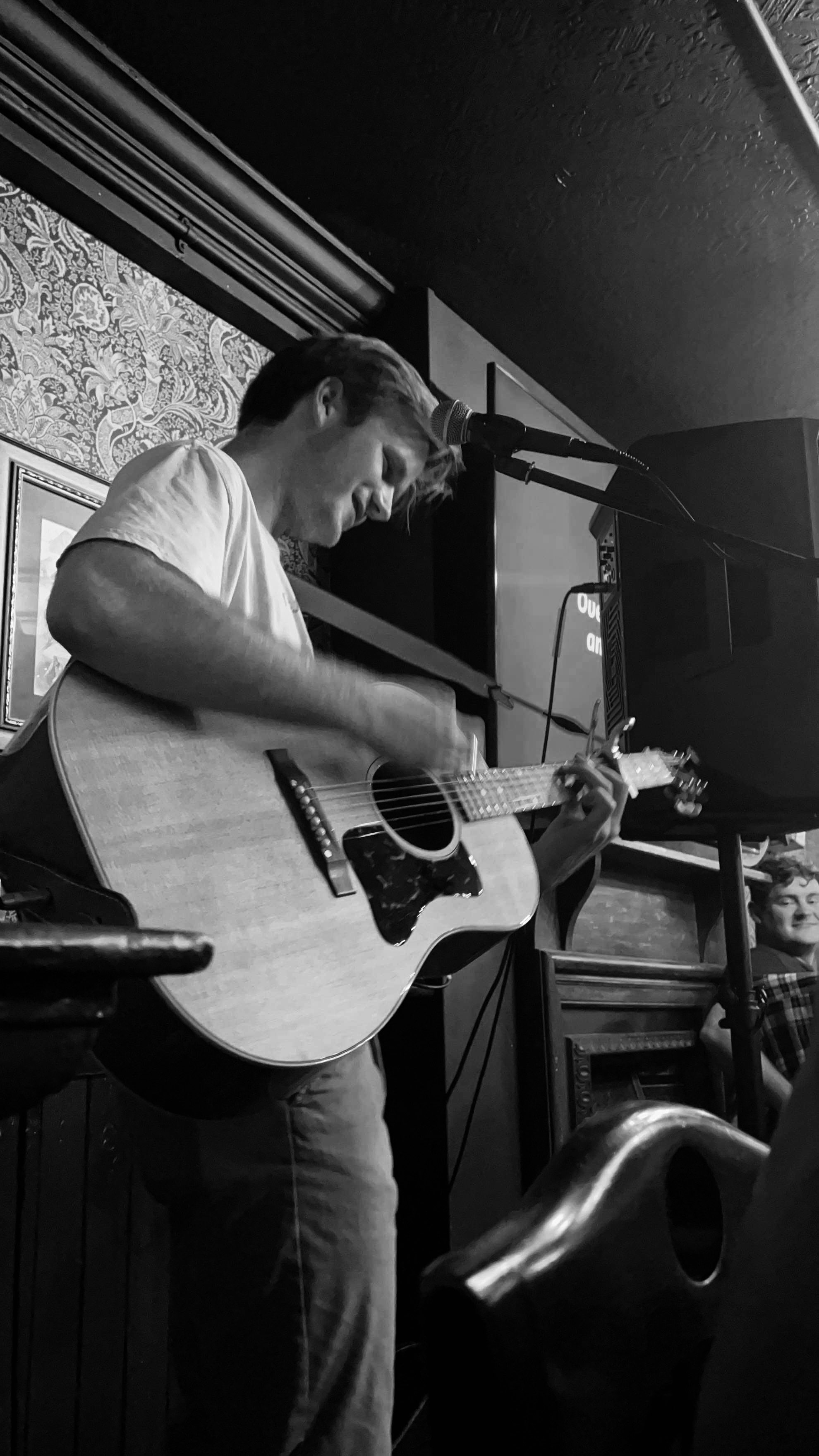 a man playing an acoustic guitar in front of a microphone