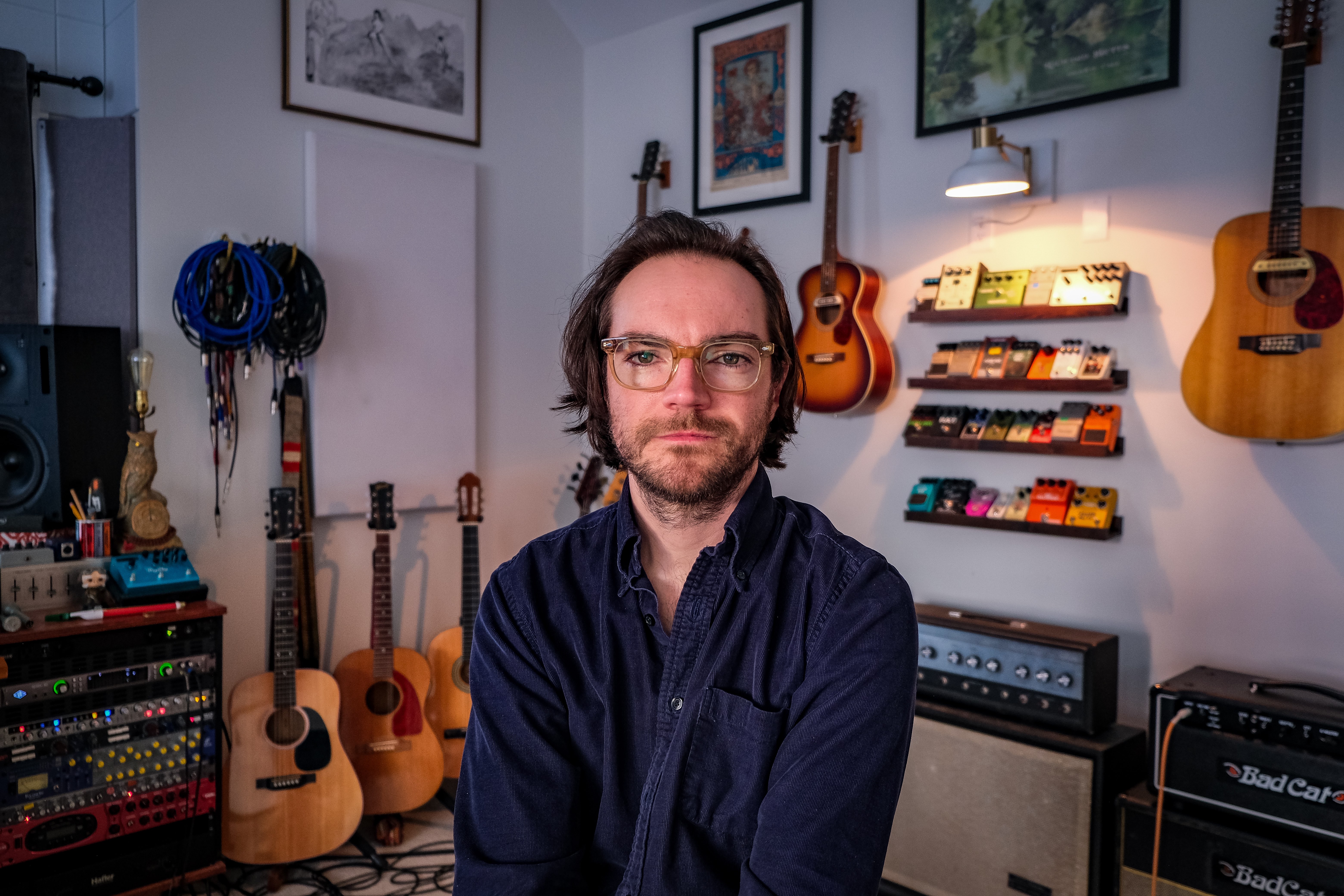 a man sitting in front of guitars in a recording studio
