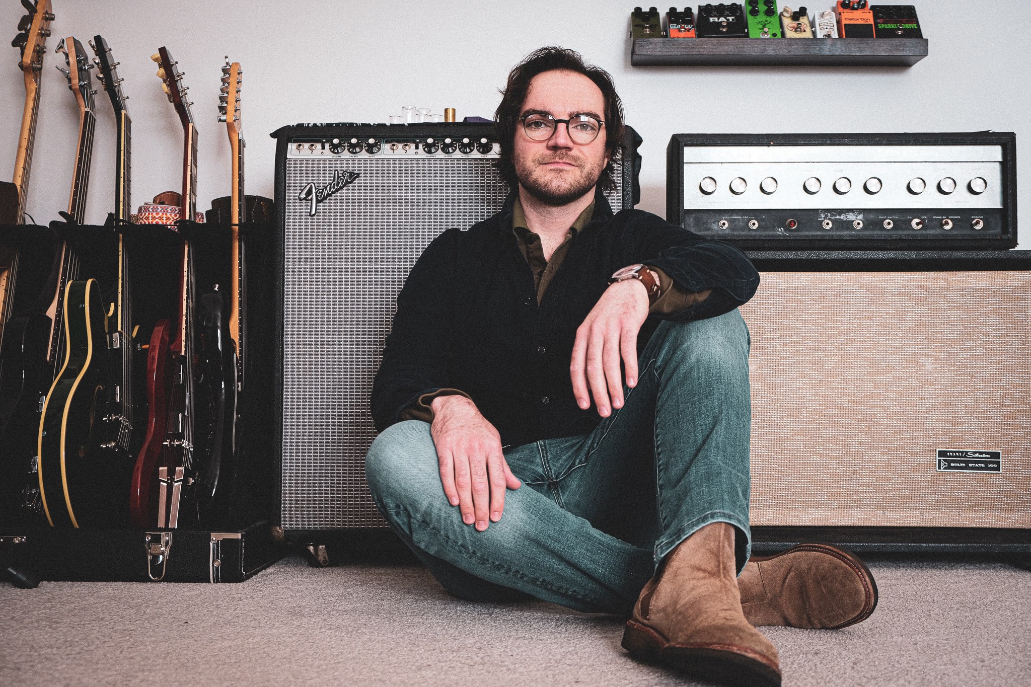 a man sitting on the floor next to a guitar amp