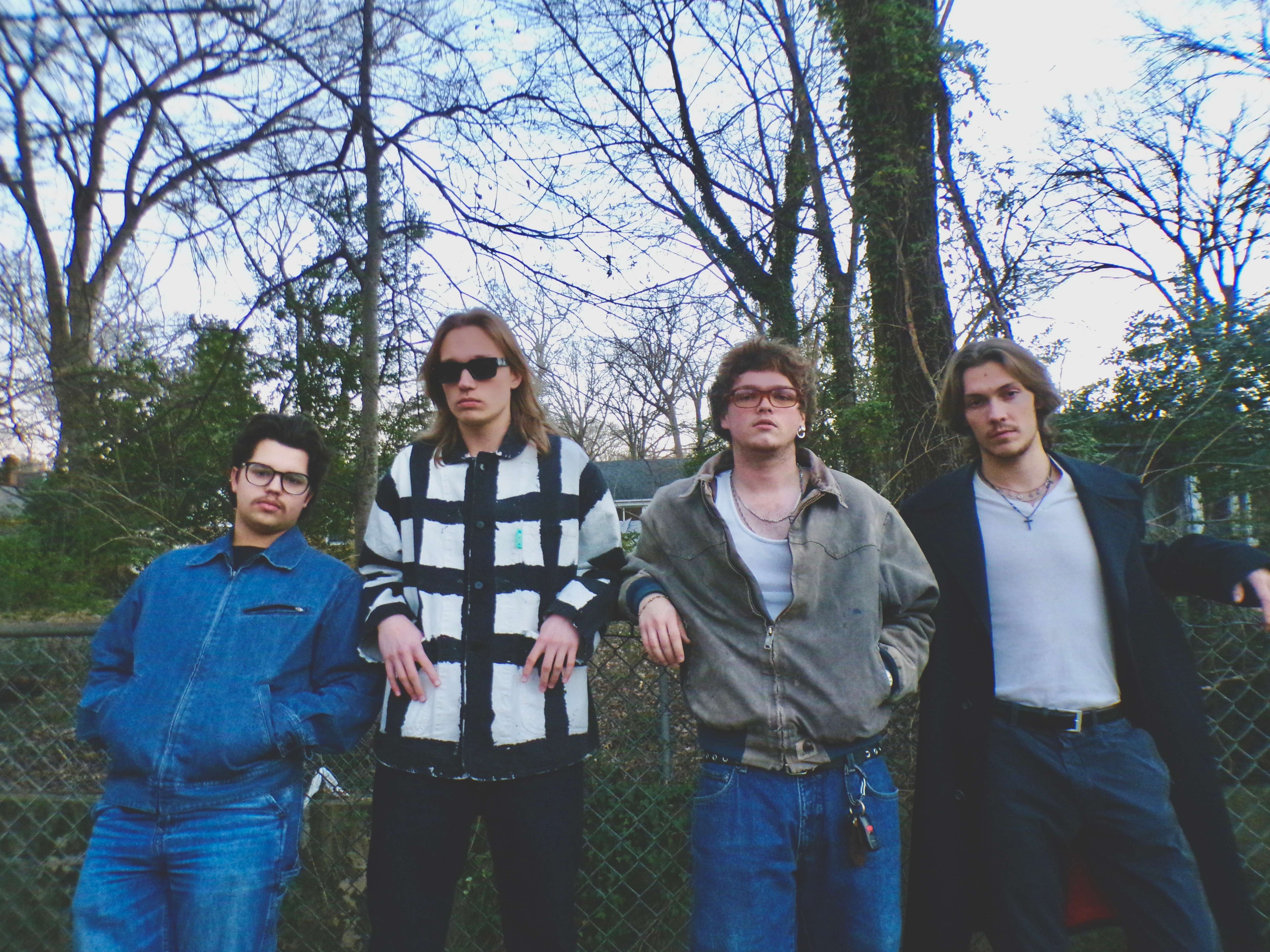 a group of young men standing in front of a fence