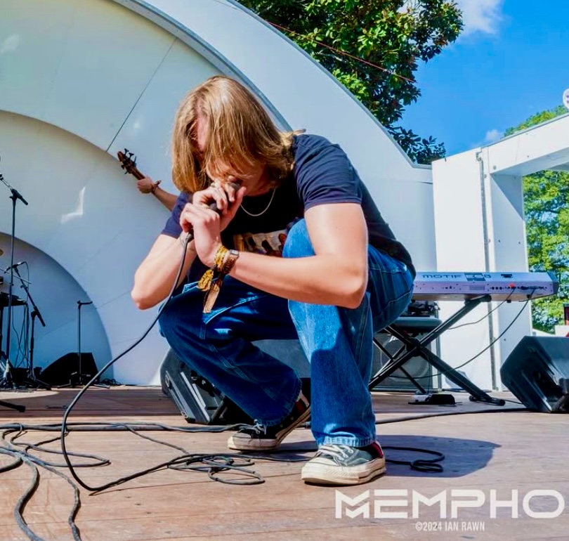 a man crouching down on a stage with a microphone