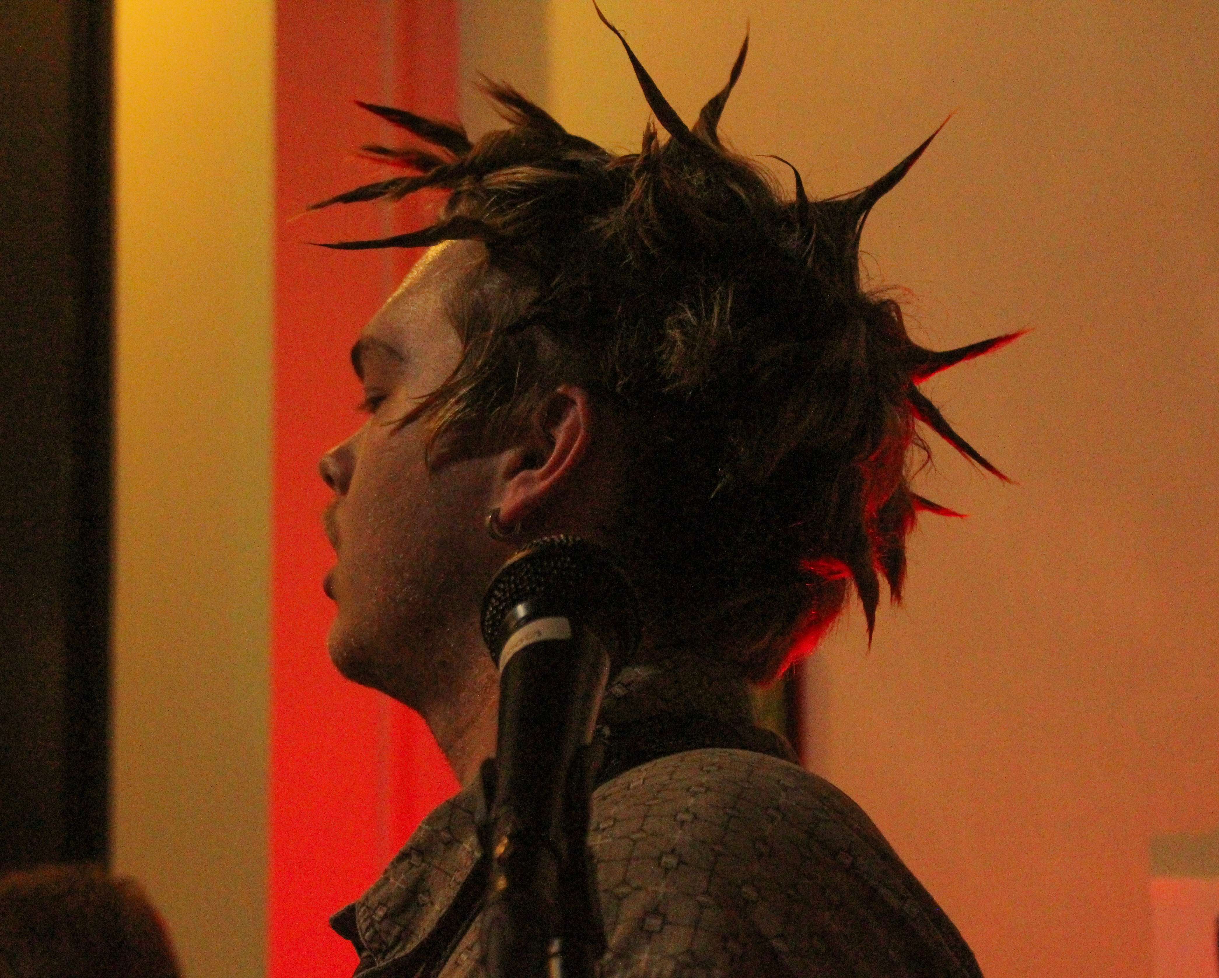 a man with spiked hair standing in front of a microphone