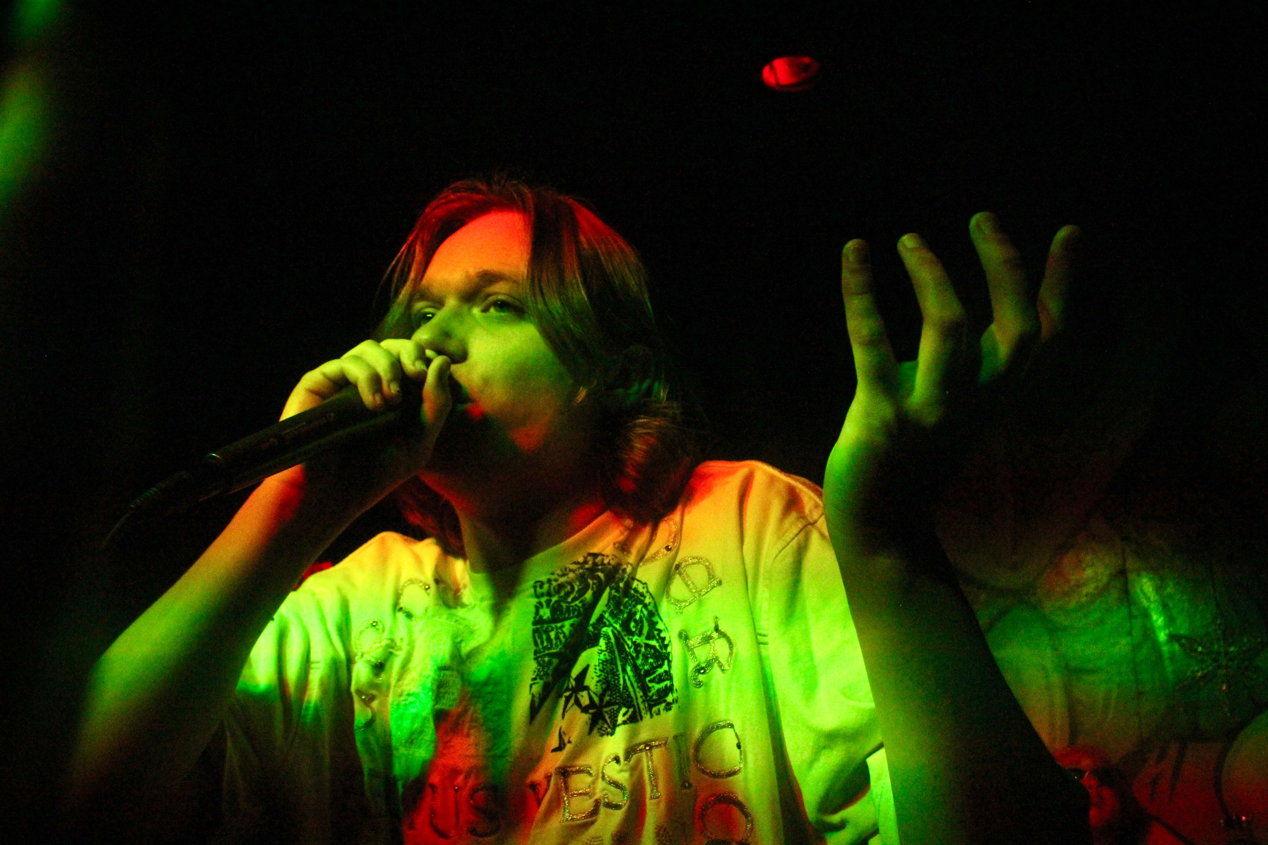 a man in a green shirt singing into a microphone