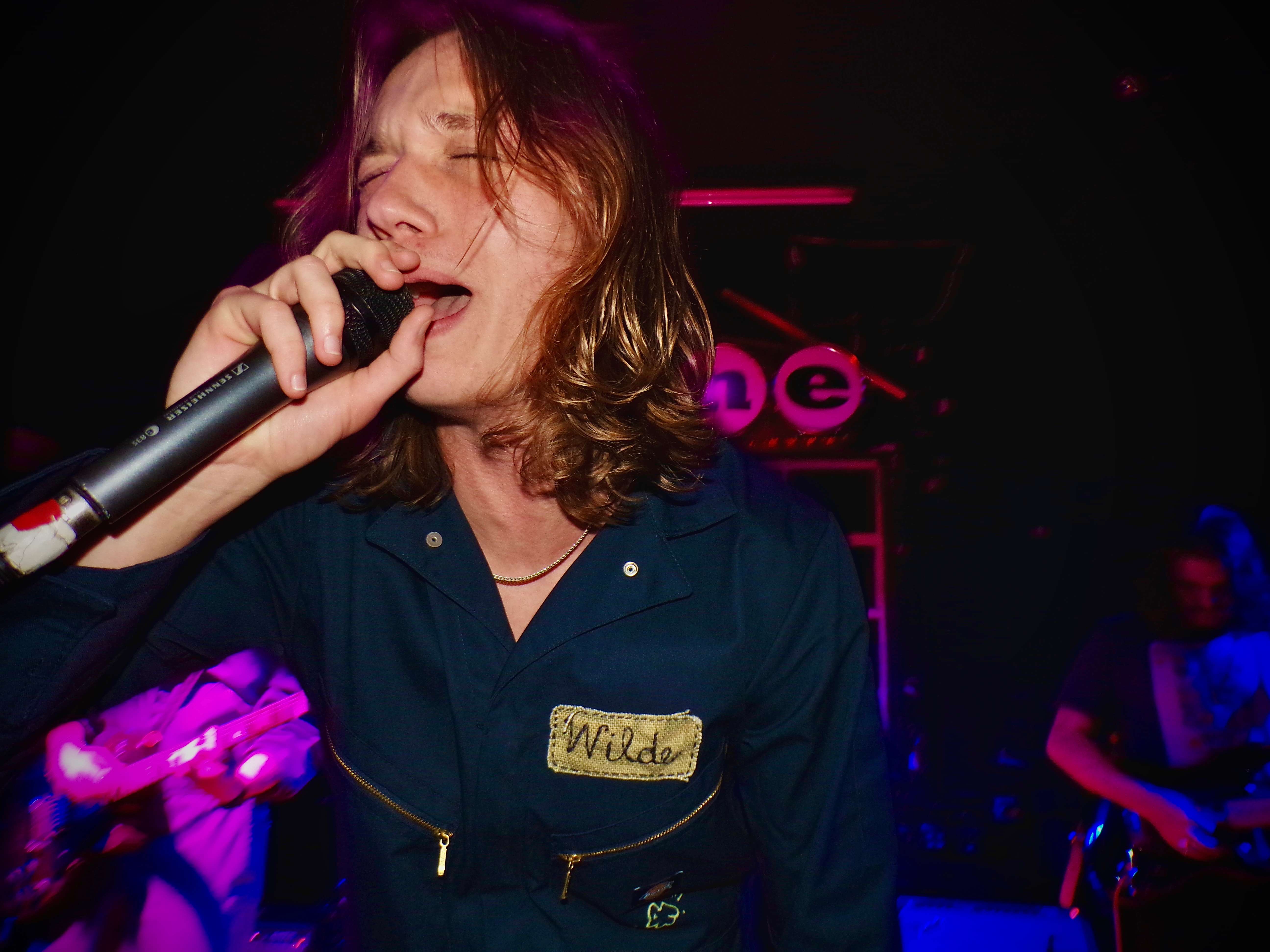 a man with long hair singing into a microphone