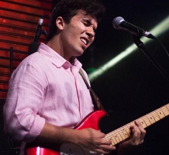 a young man playing a red guitar in front of a microphone