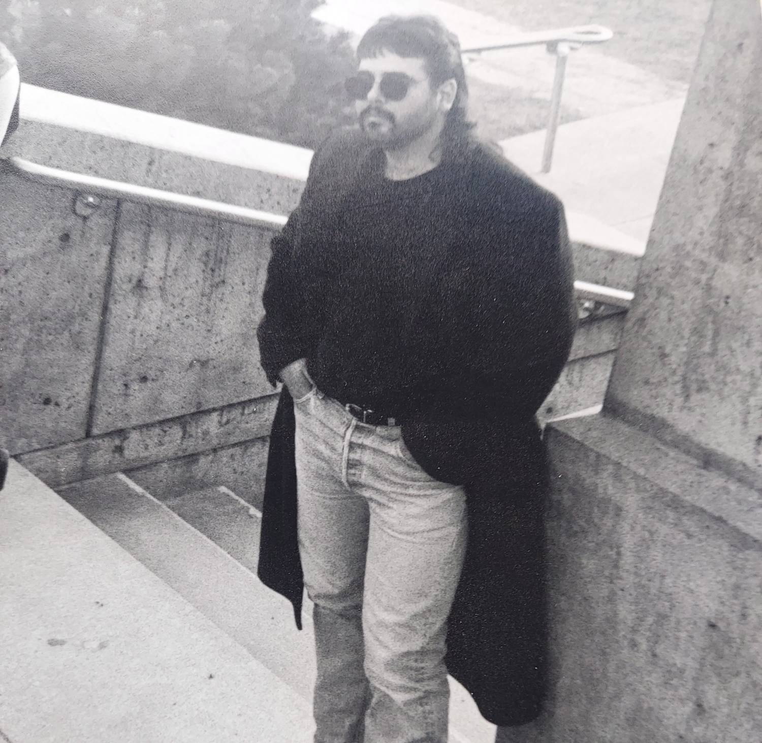 a man in a coat and jeans standing on steps