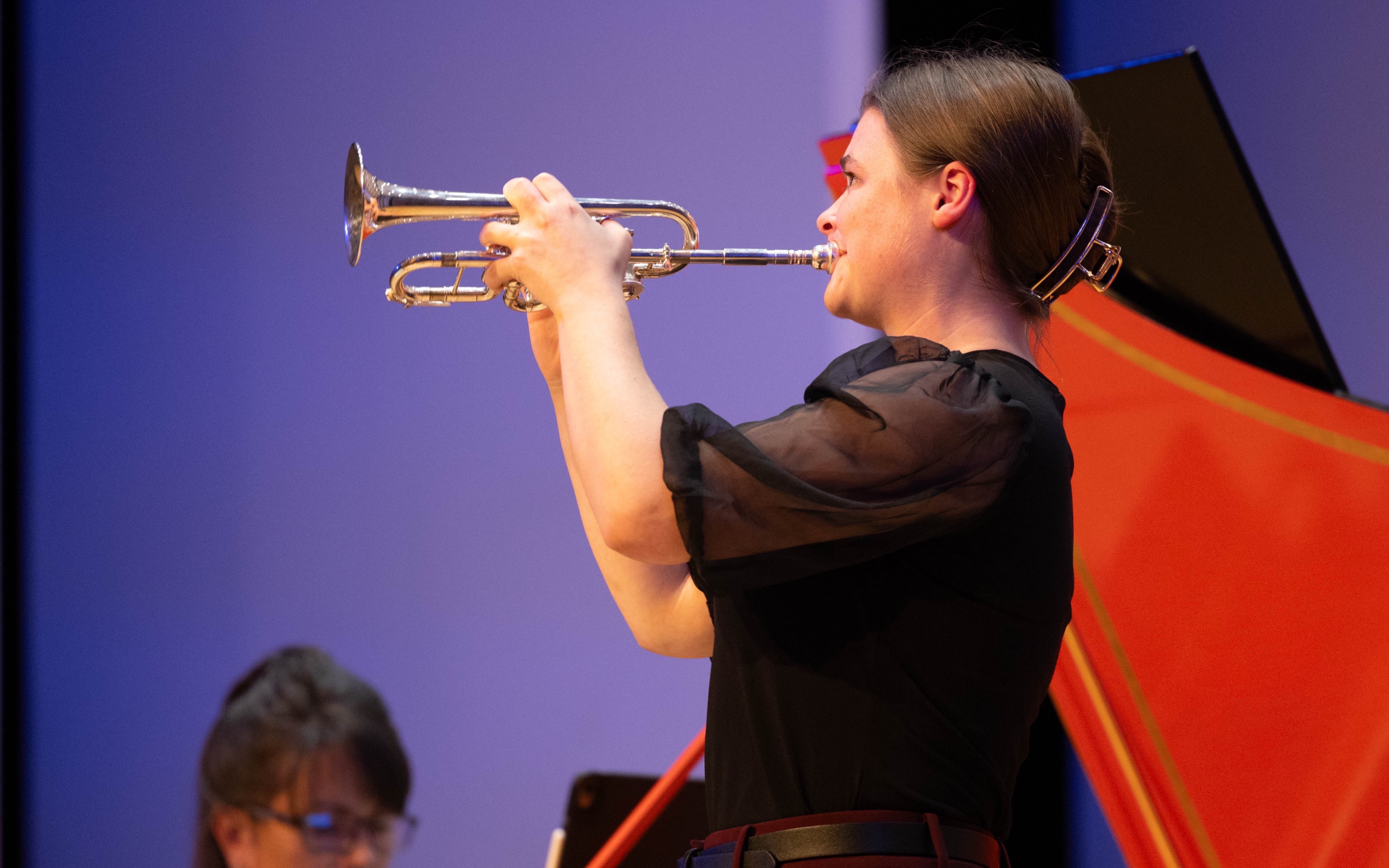 a woman playing a trumpet in front of an audience