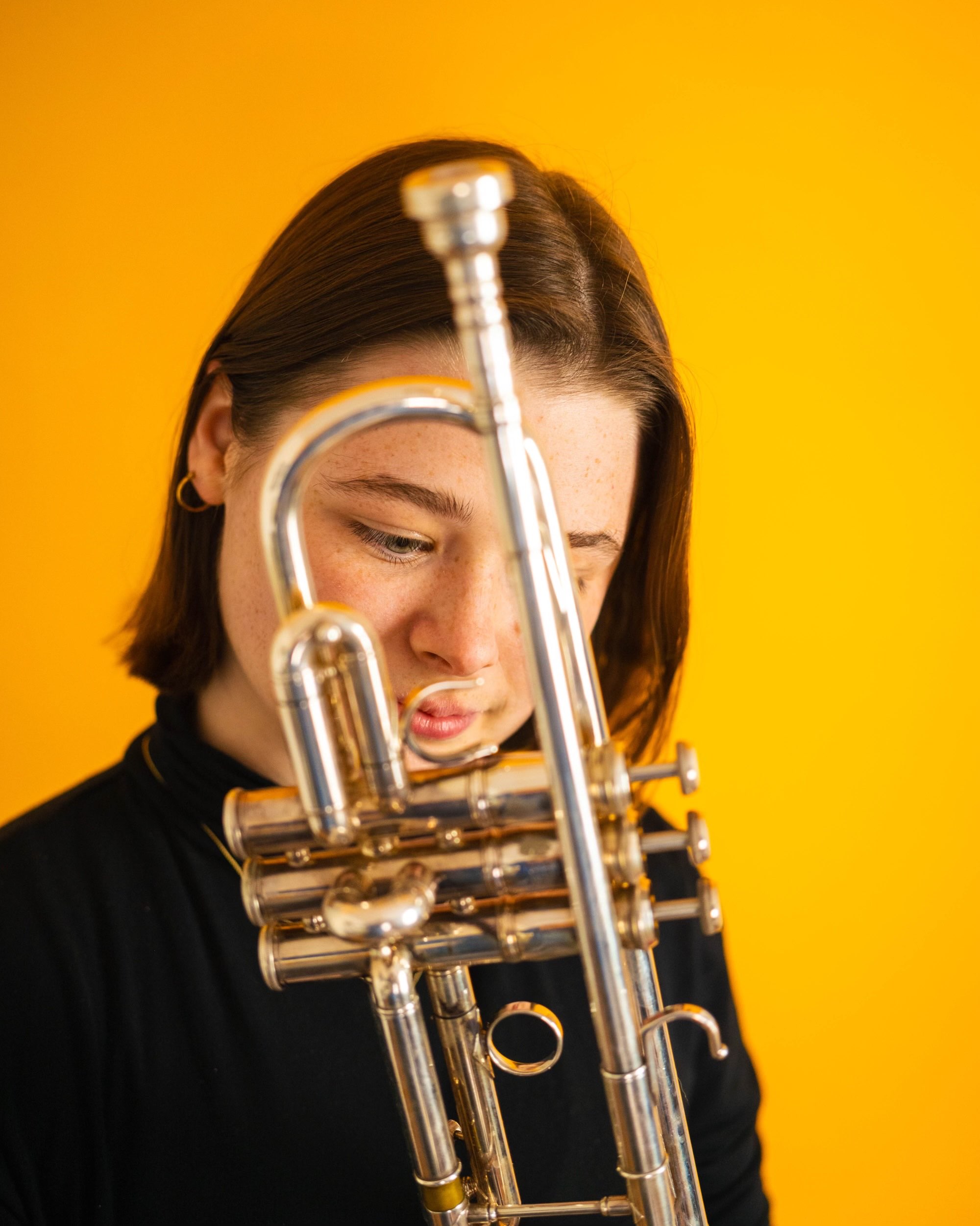 a woman holding a trumpet against an orange background