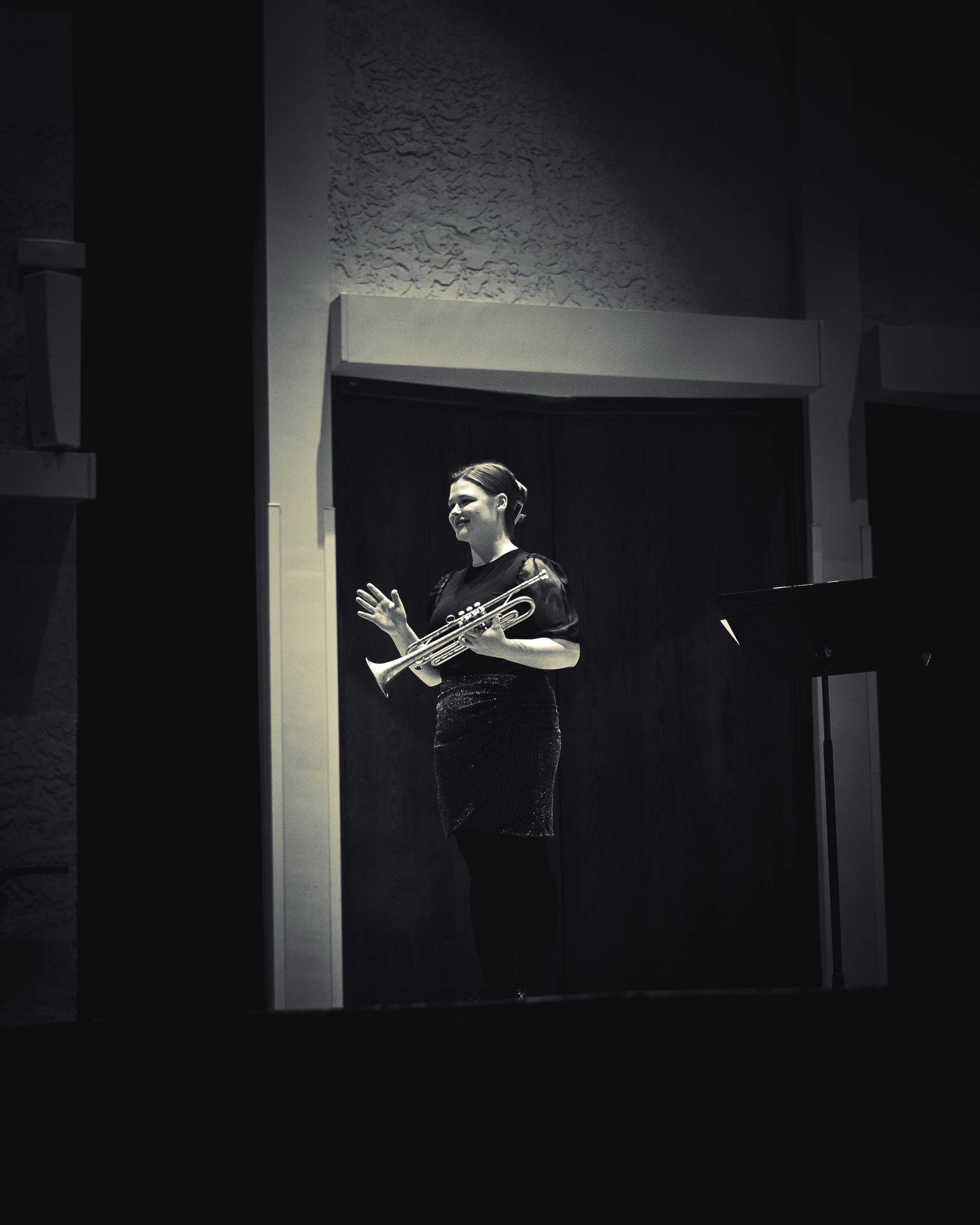 a black and white photo of a woman standing in front of a stage