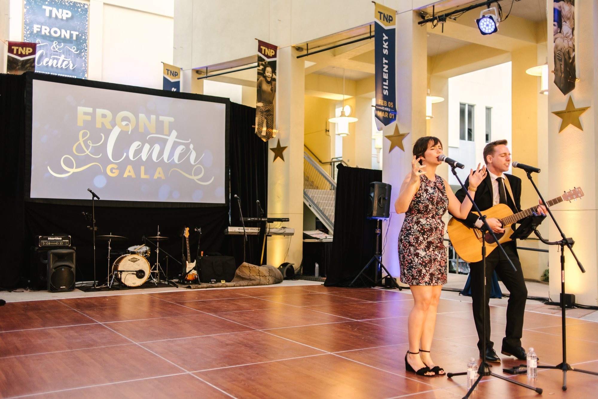 a man and woman singing in front of a large stage