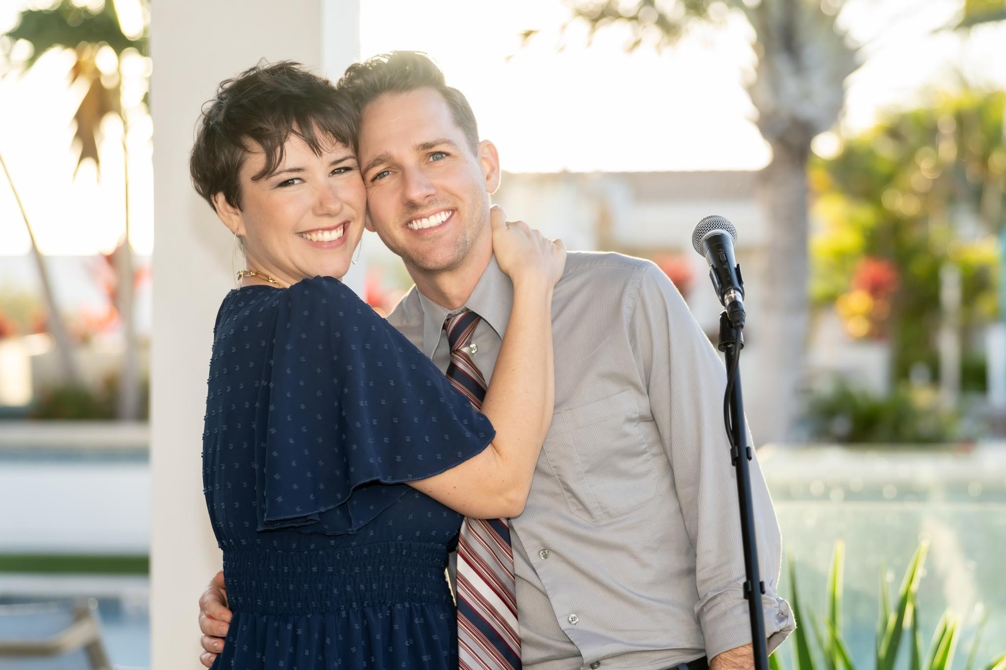 a man and woman hugging in front of a microphone