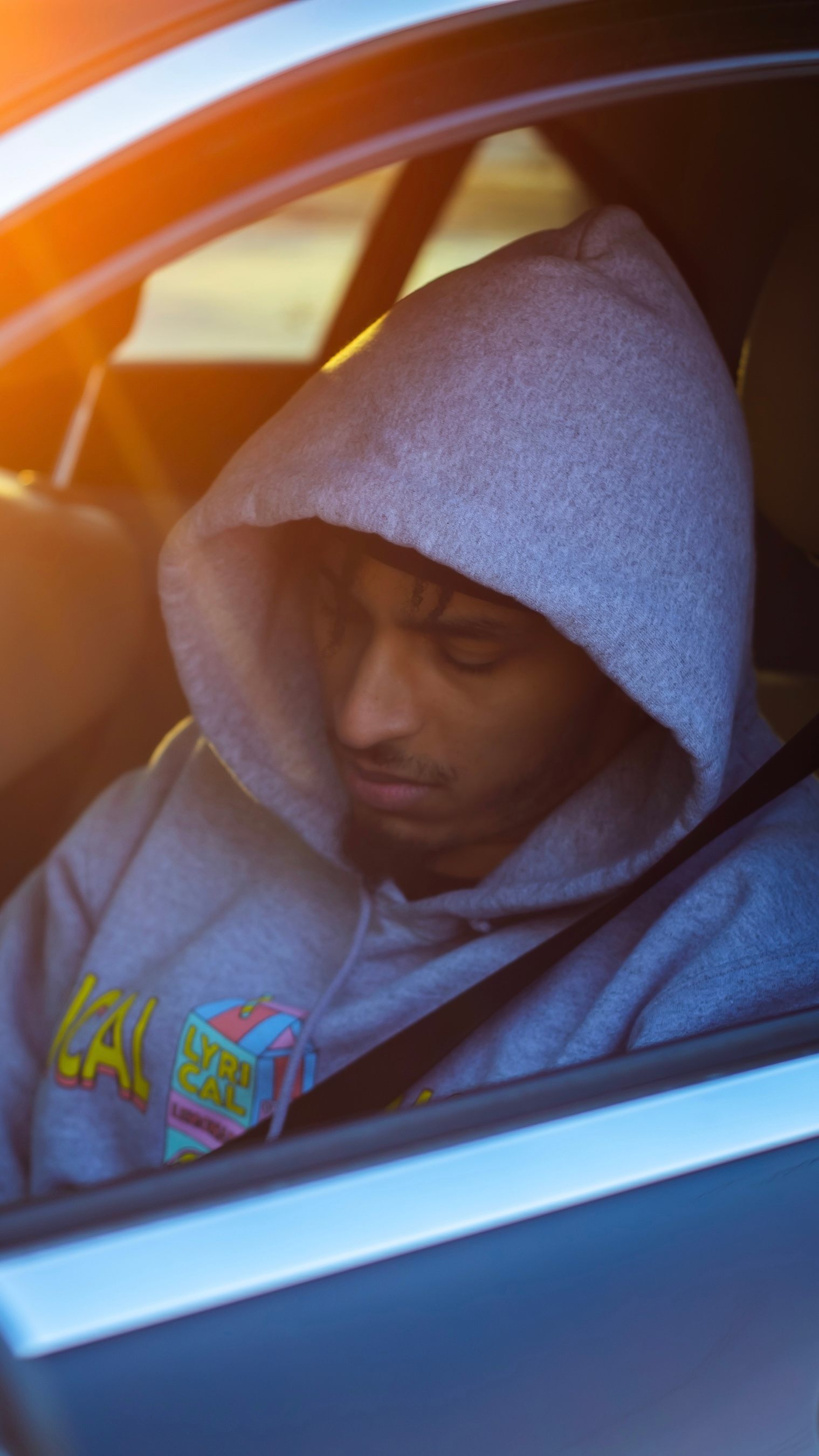 a man in a hoodie sitting in a car