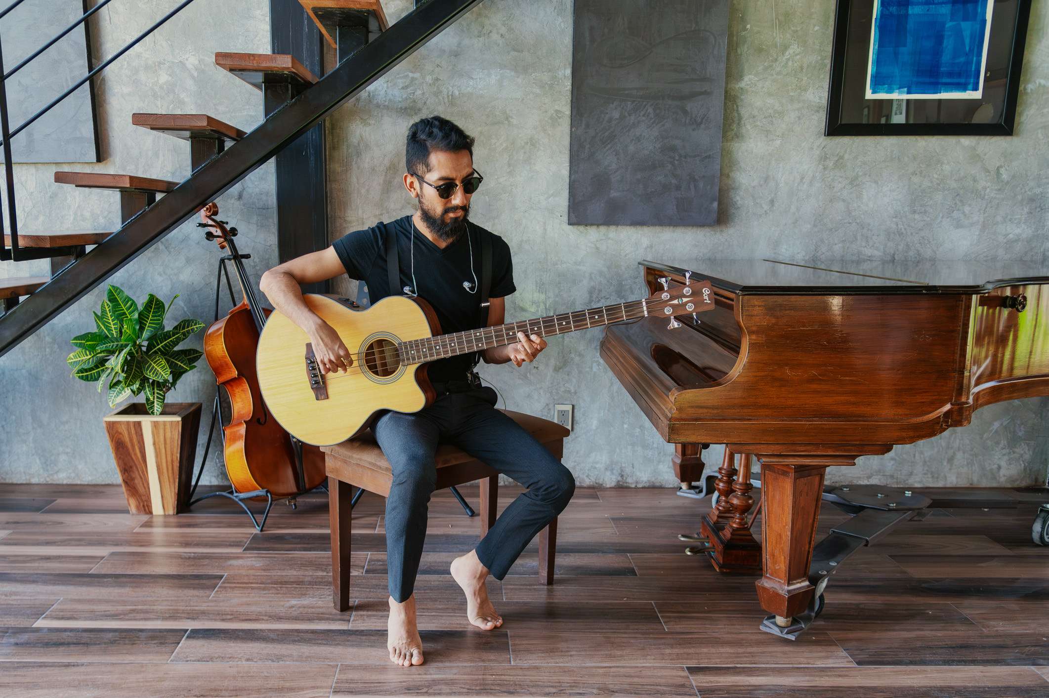a man playing an acoustic guitar in front of a piano