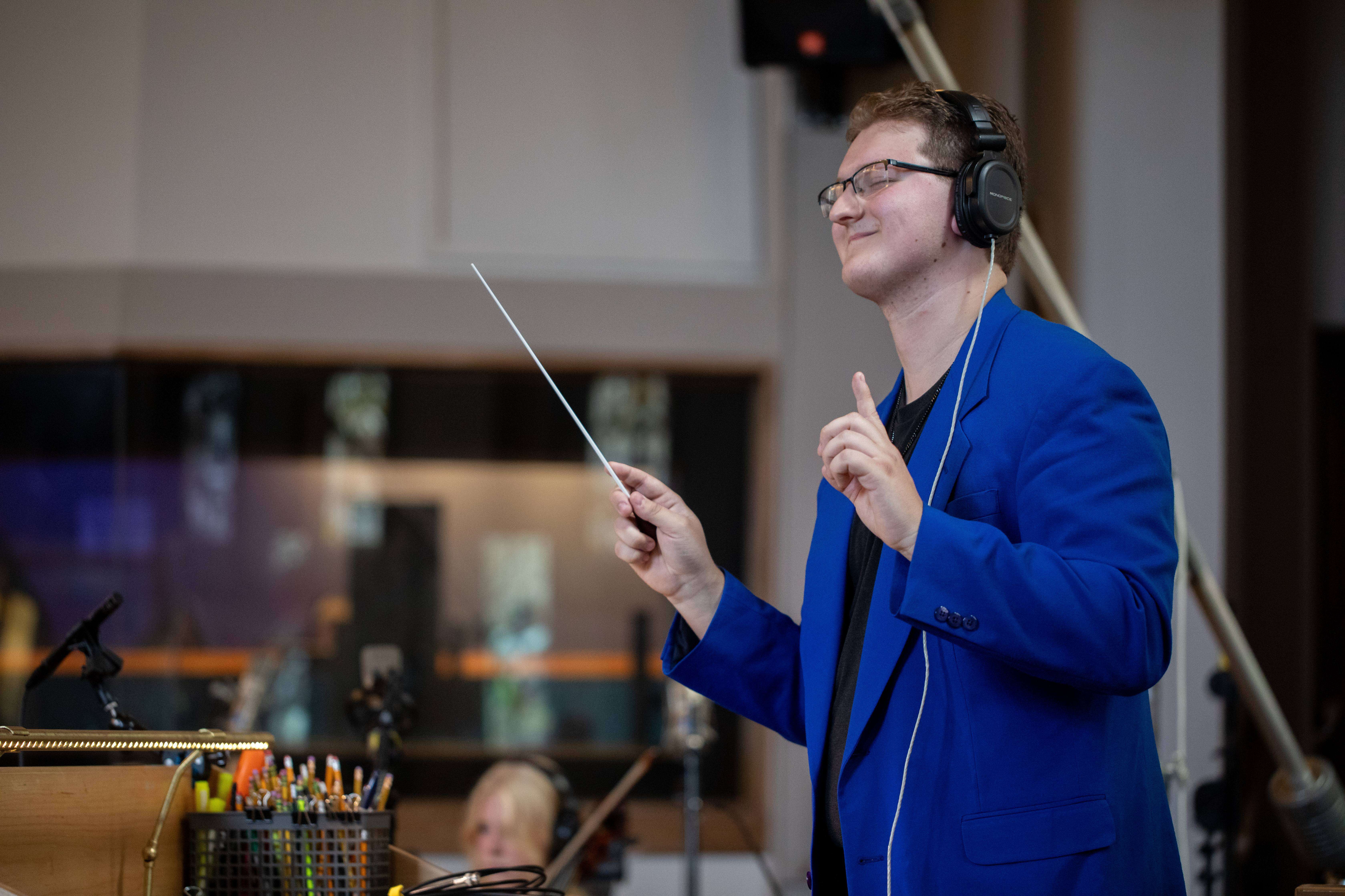 a man in a blue jacket is holding a conductor's baton