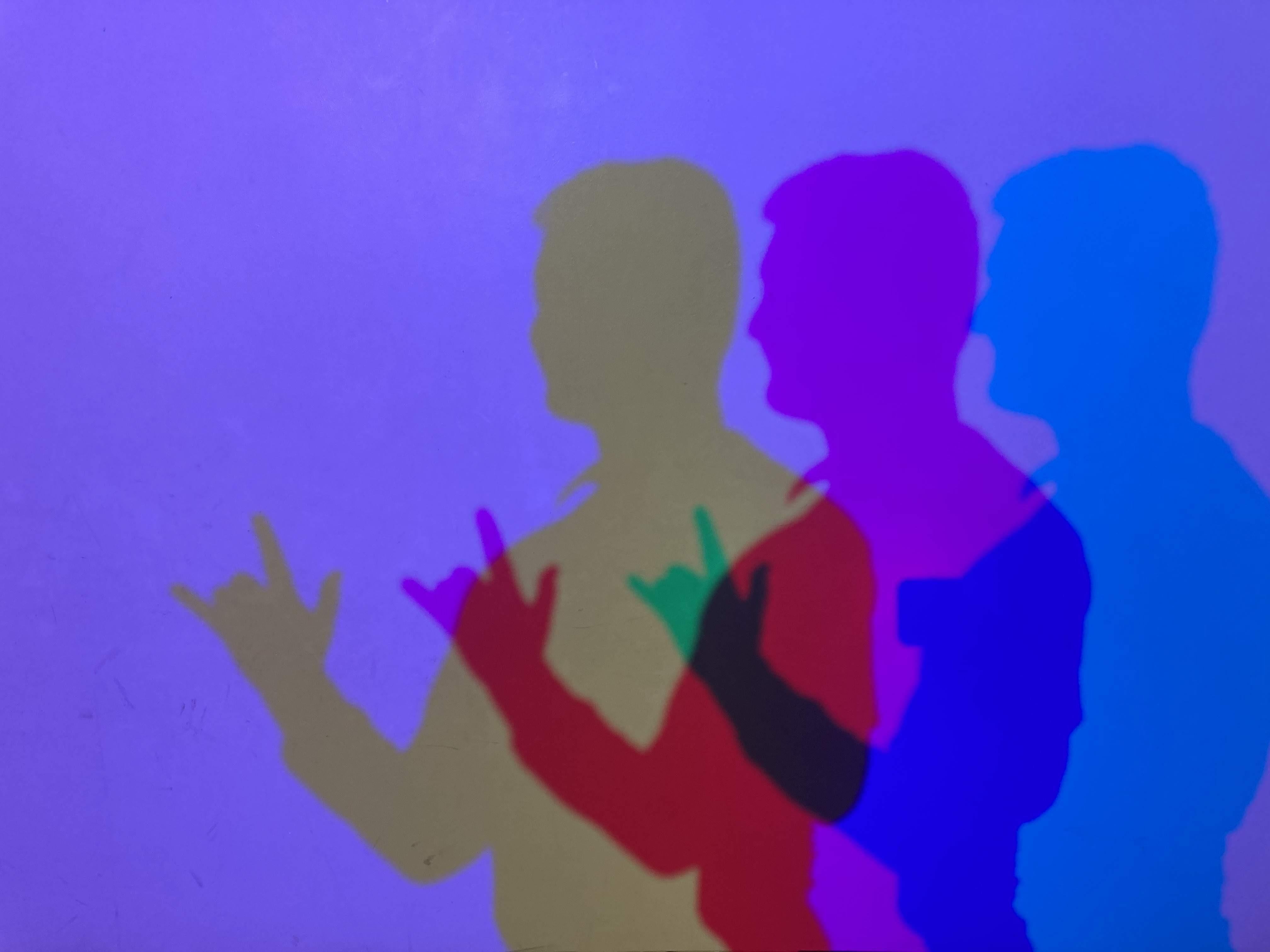 three shadows of people standing in front of a purple wall