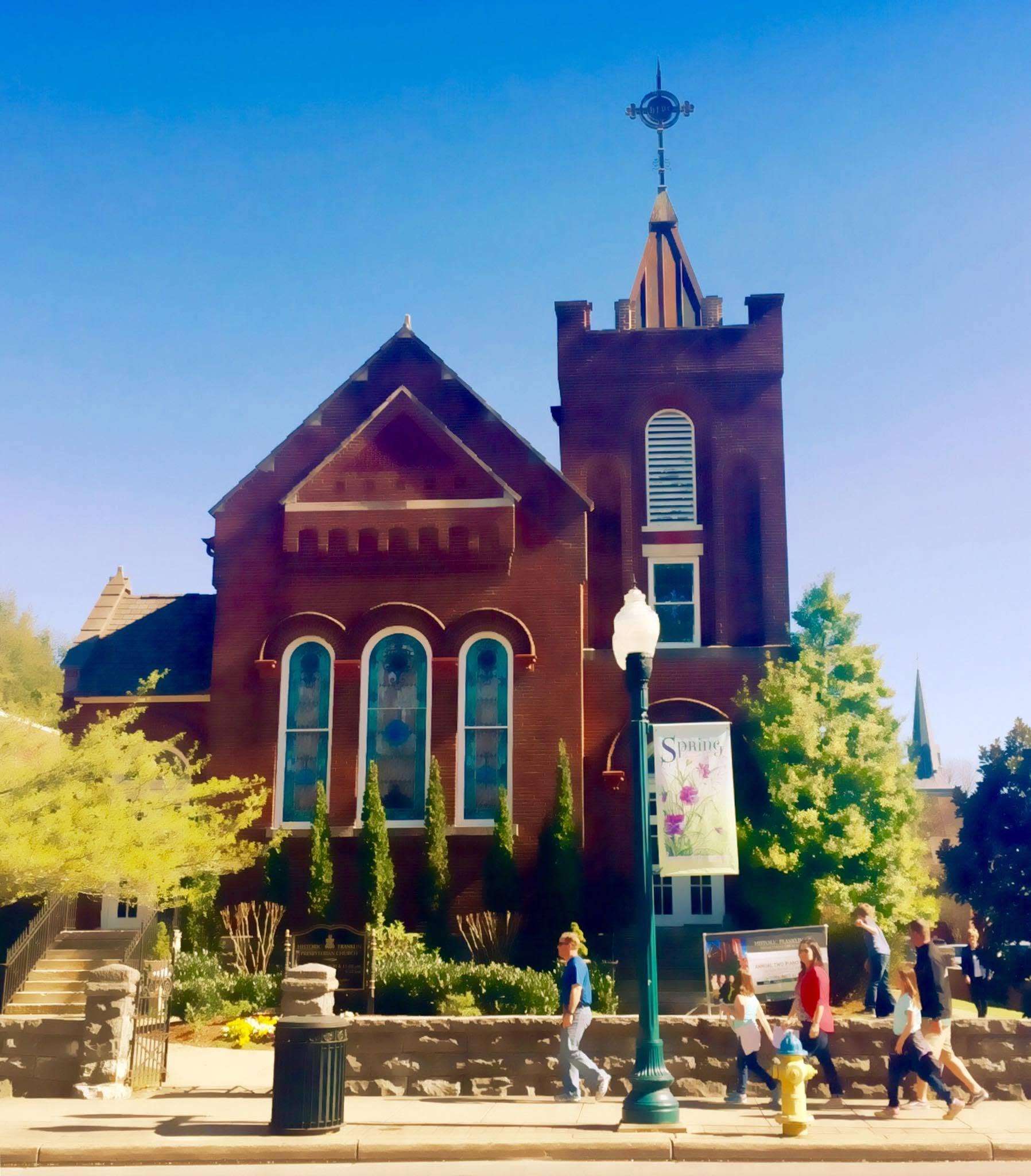 a red brick church with people walking in front of it