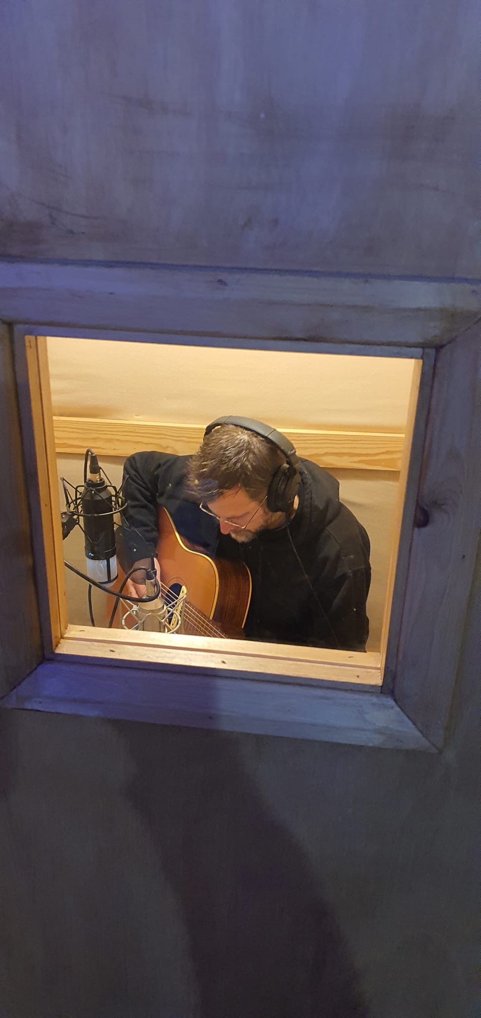 a man playing an acoustic guitar in a recording studio