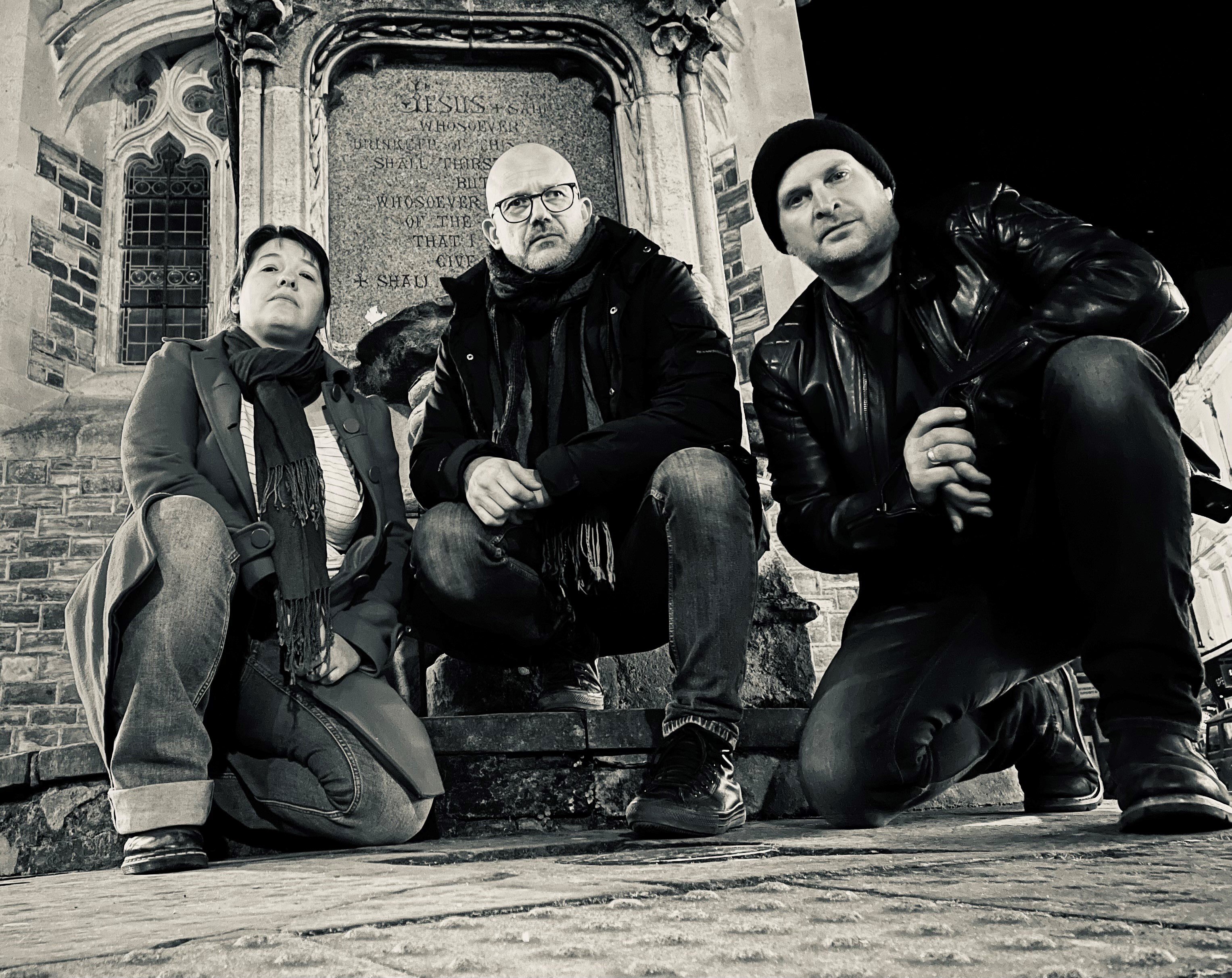 three people posing in front of a building