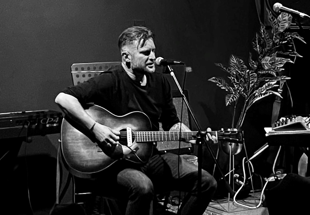 a man playing an acoustic guitar in front of a microphone