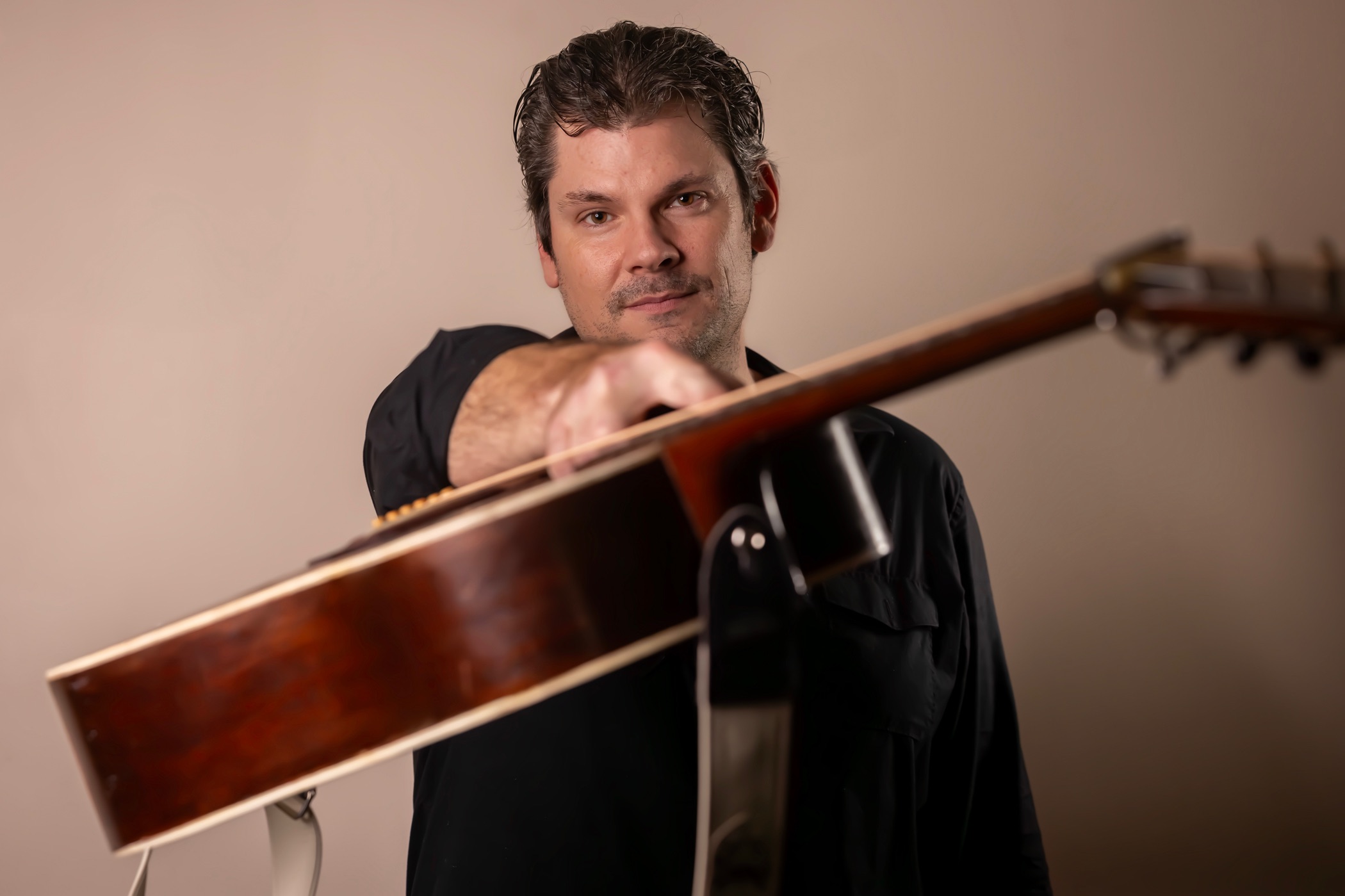 a man holding an acoustic guitar in front of a white background