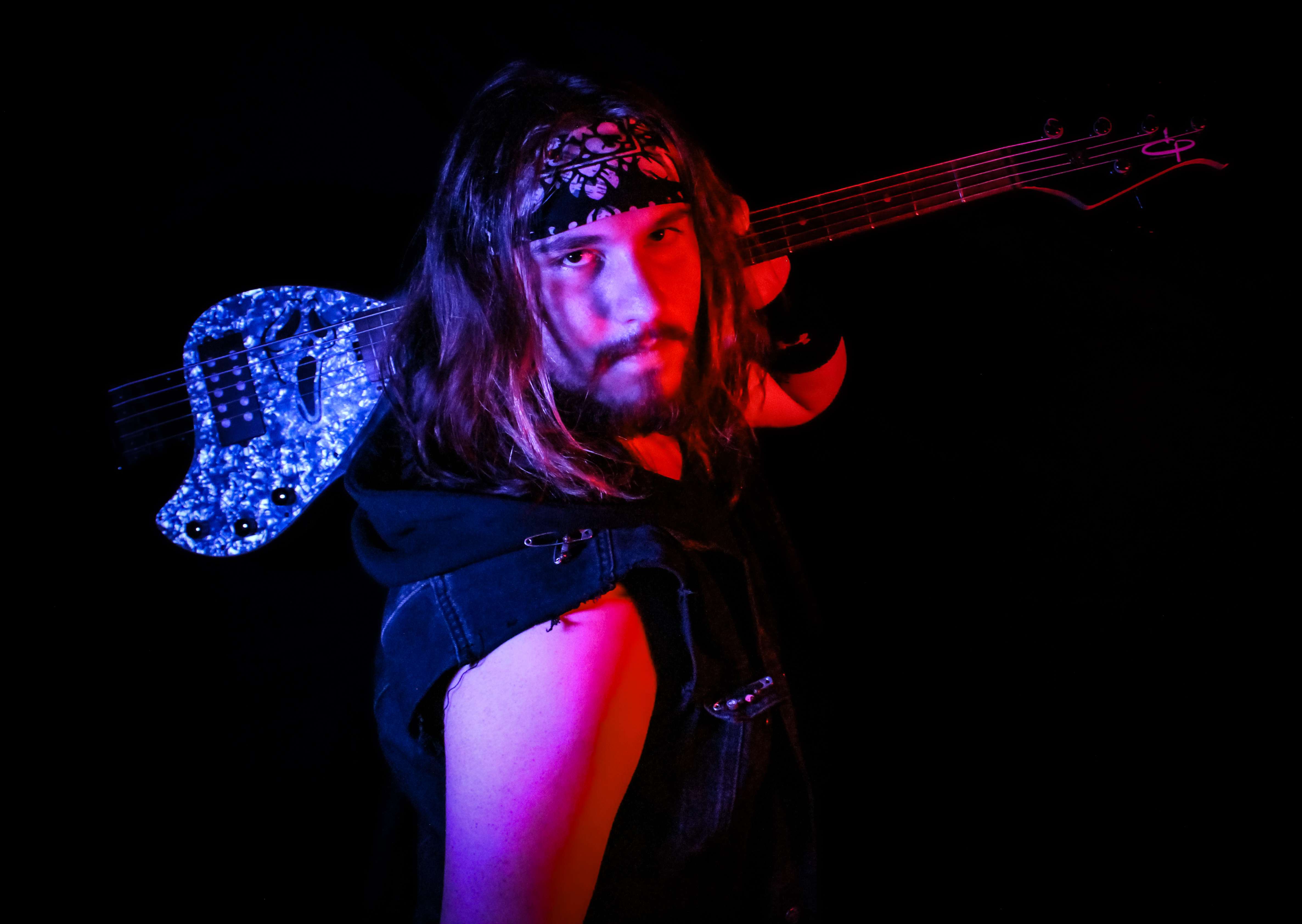 a man with long hair holding a guitar in front of a dark background