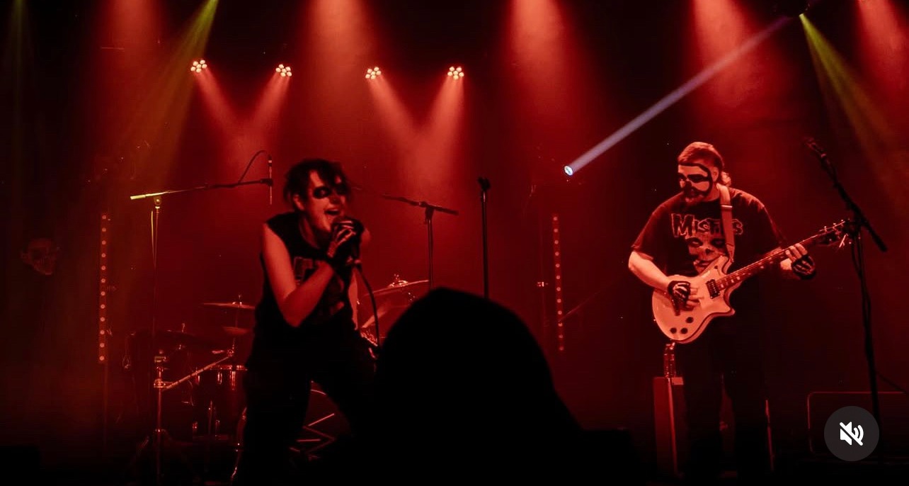 a band performs on stage in front of red lights