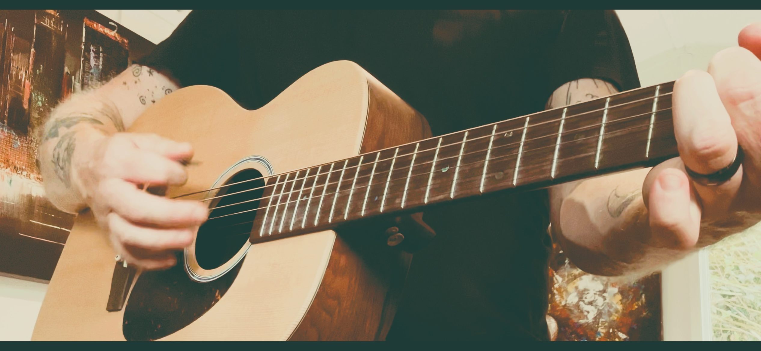a man with tattoos playing an acoustic guitar