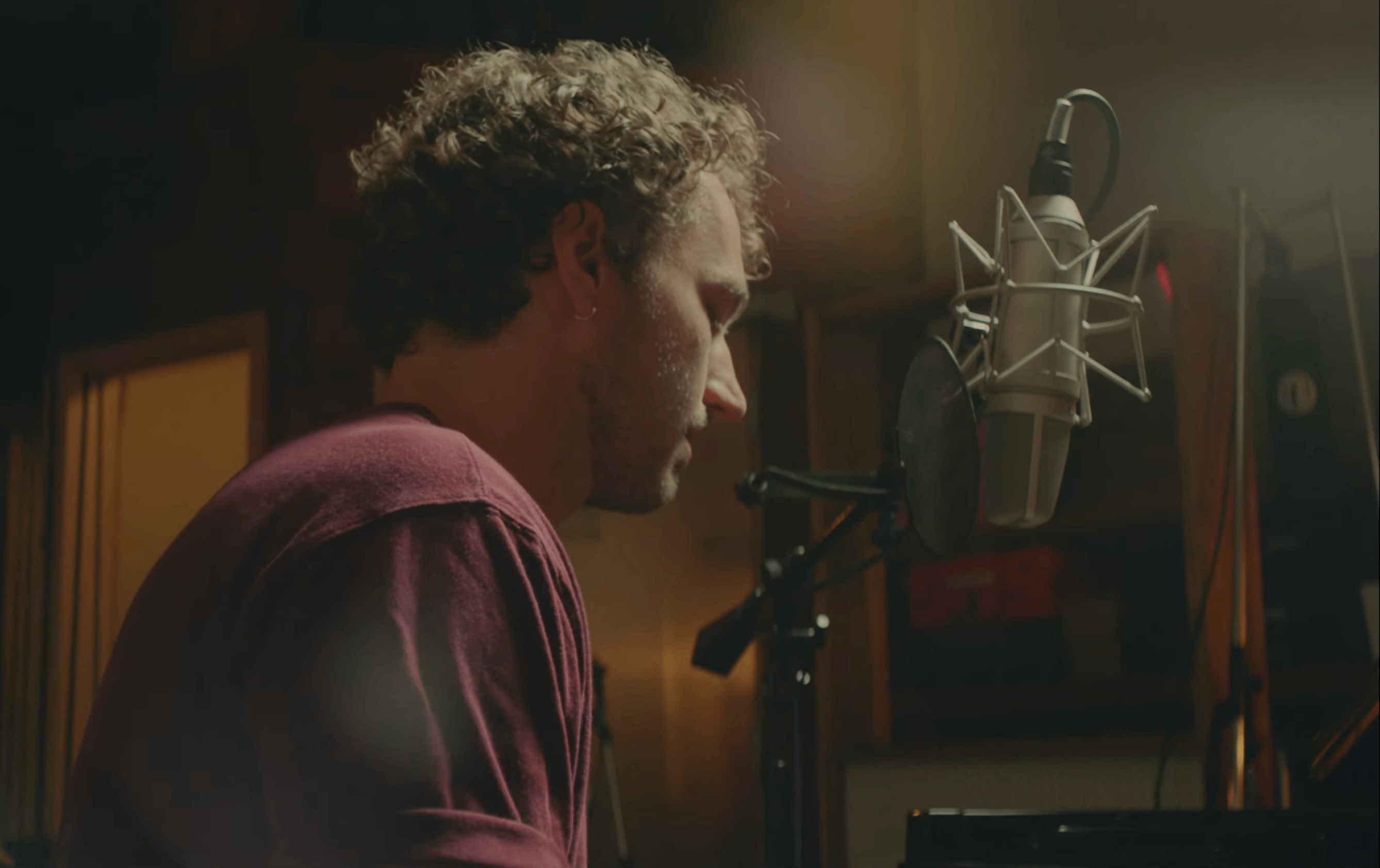 a man sitting in front of a microphone in a recording studio