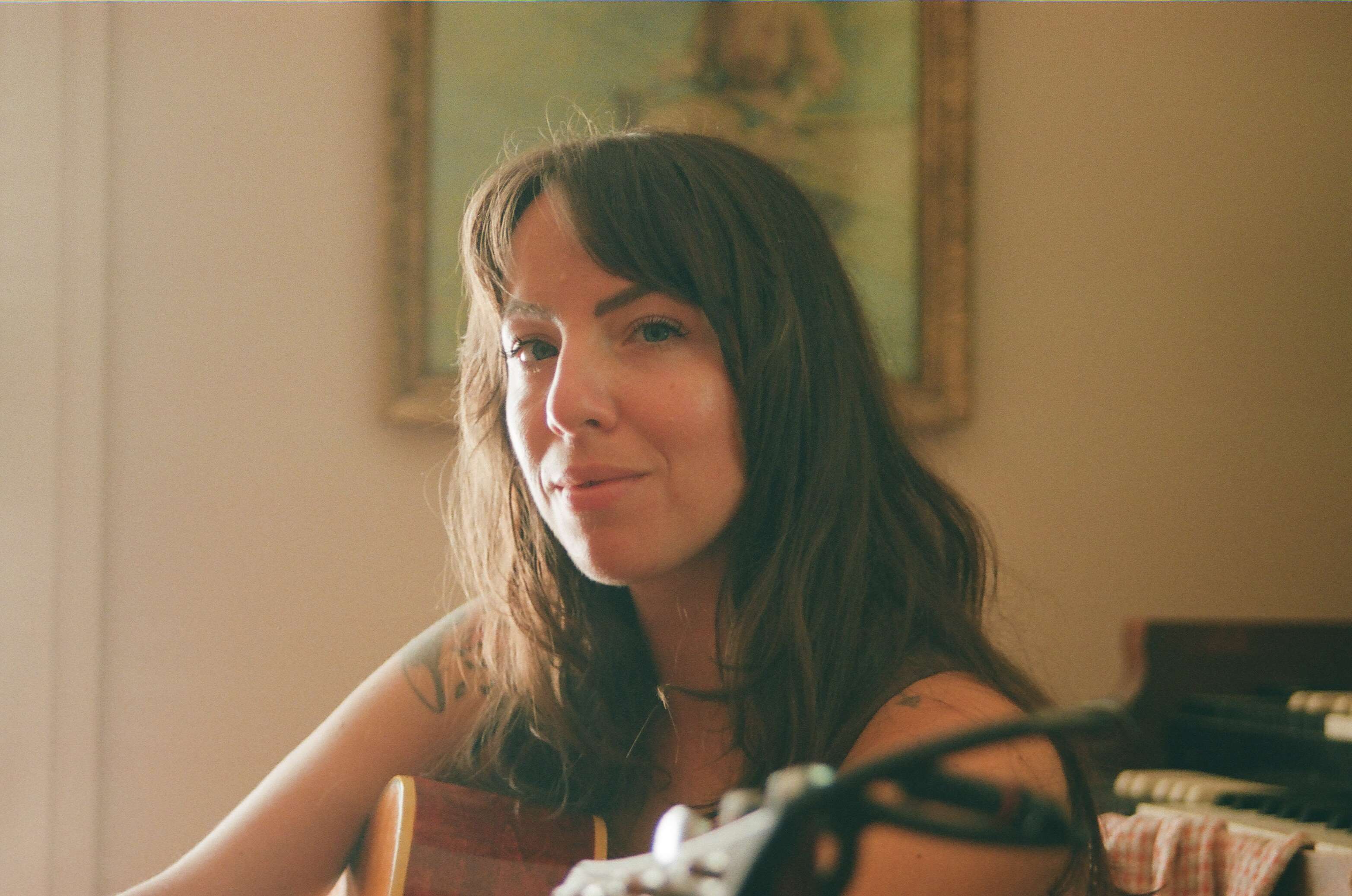 a woman sitting in a room with an acoustic guitar