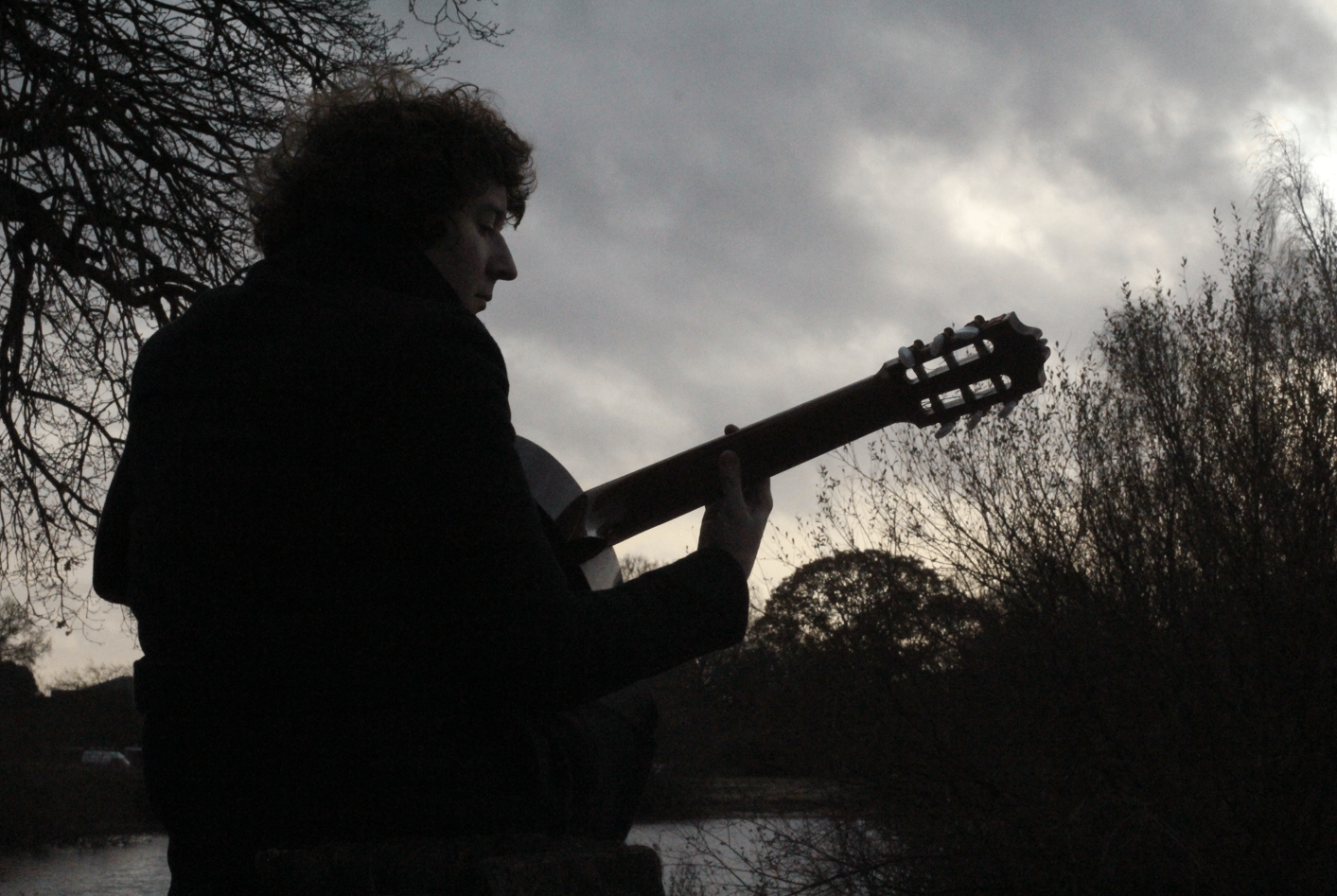 a man holding a guitar in front of a tree