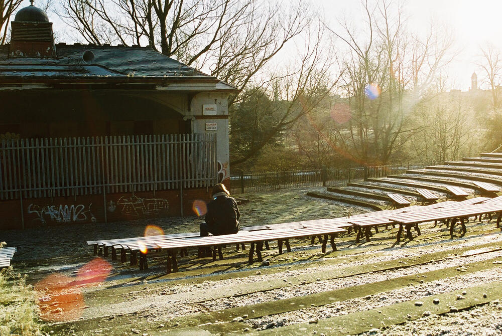 a person is sitting on a bench in a park