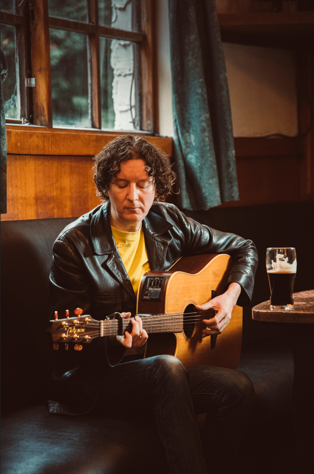 a man sitting on a couch playing an acoustic guitar