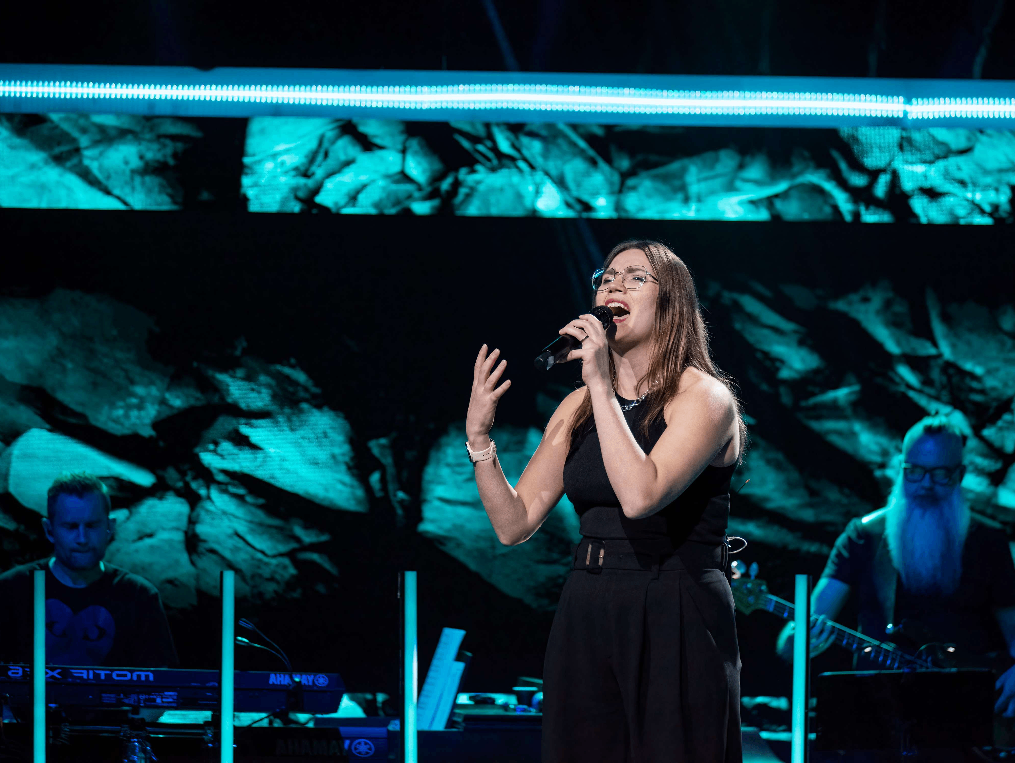 a woman singing into a microphone on stage