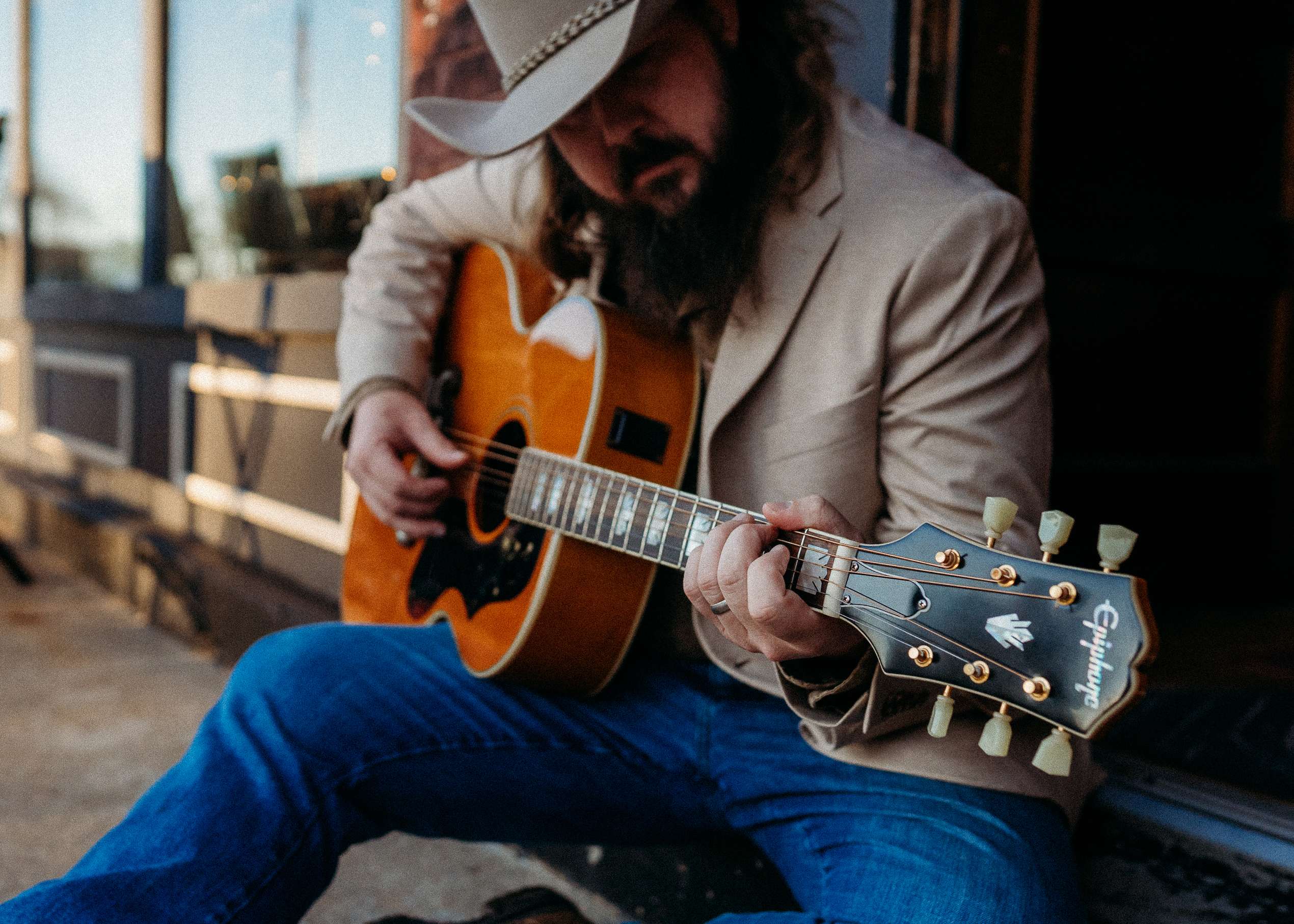 a man in a cowboy hat playing an acoustic guitar