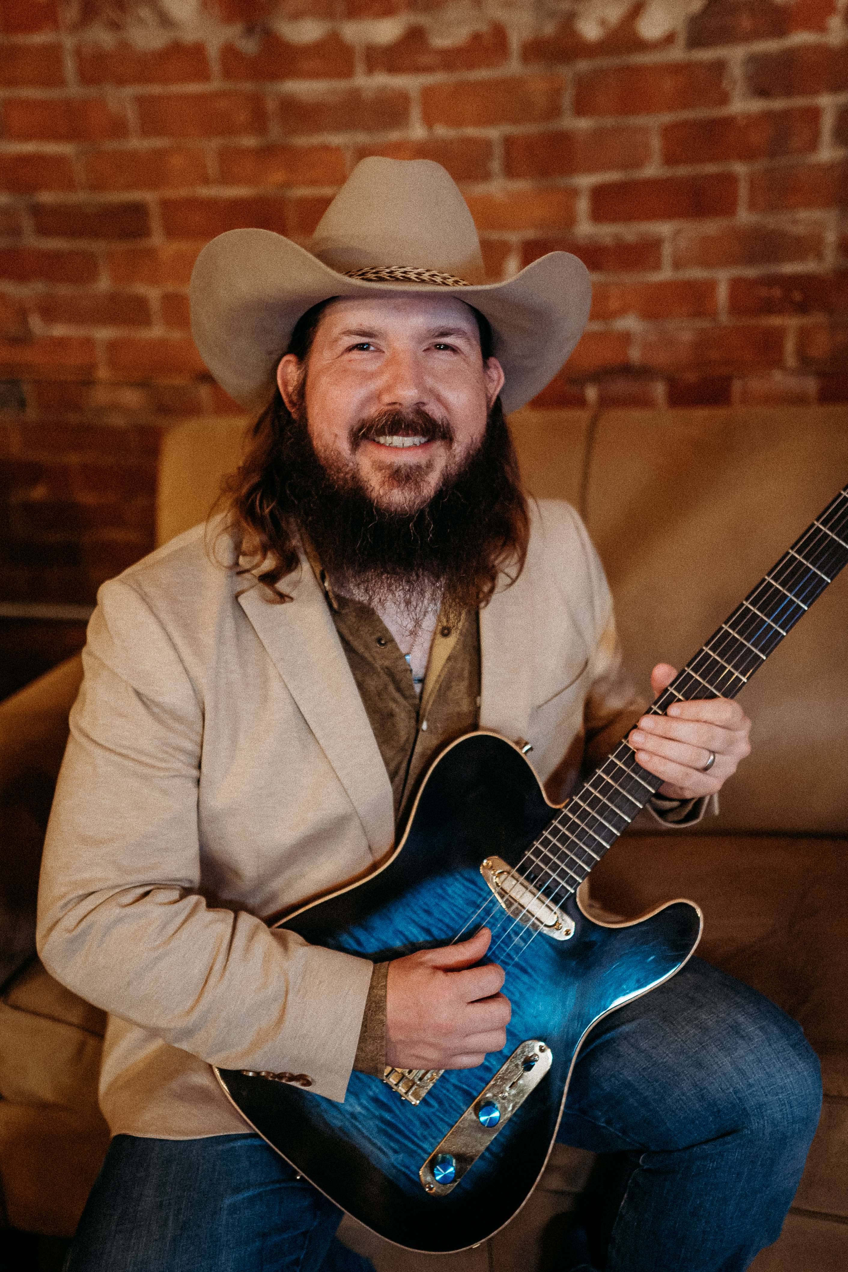 a man in a cowboy hat holding a blue guitar