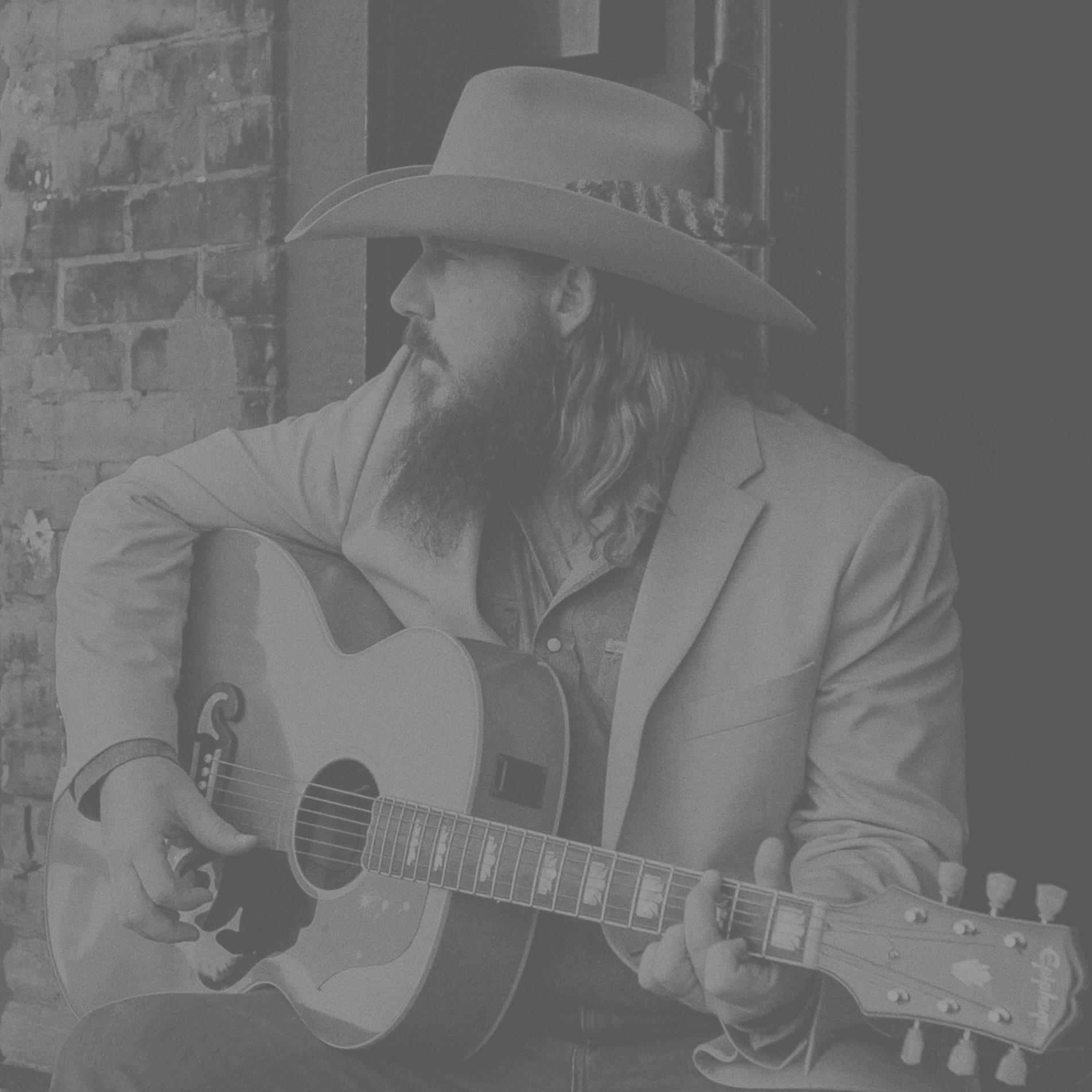 a man in a cowboy hat playing an acoustic guitar
