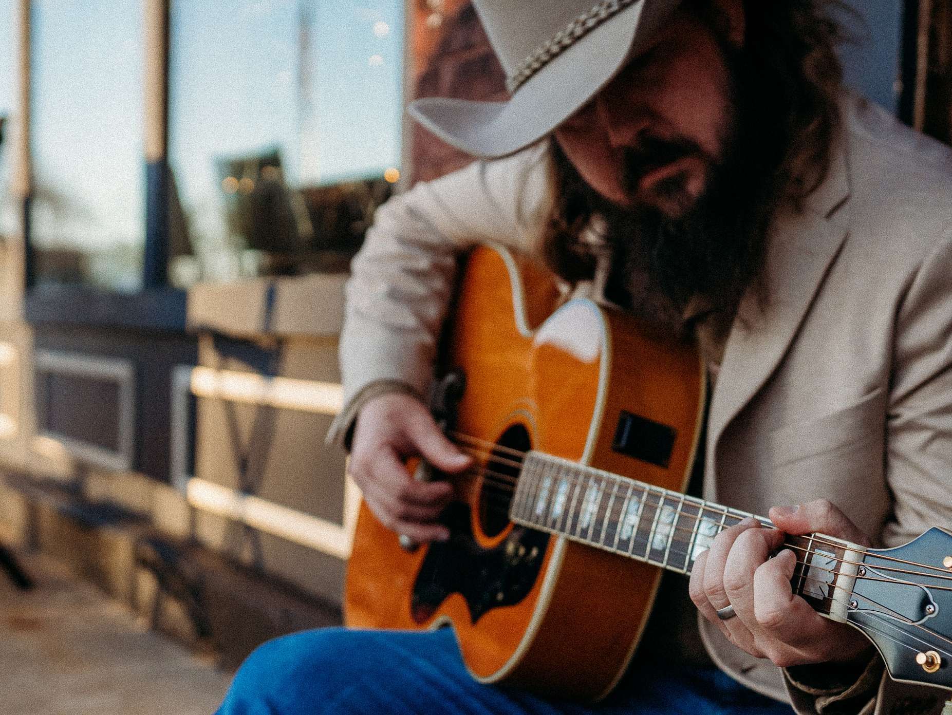 a man in a cowboy hat playing an acoustic guitar