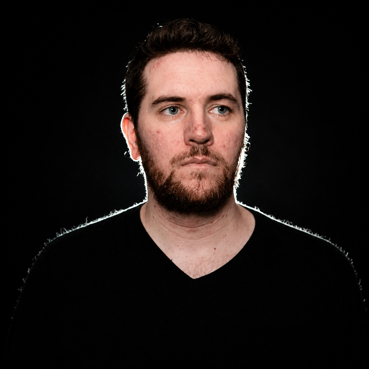 a man with a beard is standing in front of a black background