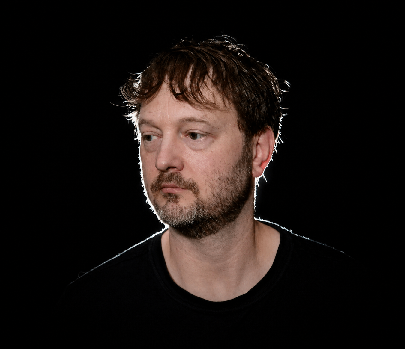 a man in a black shirt is staring at a black background