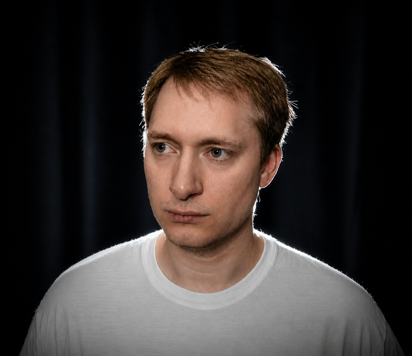 a man in a white t - shirt is staring at the camera